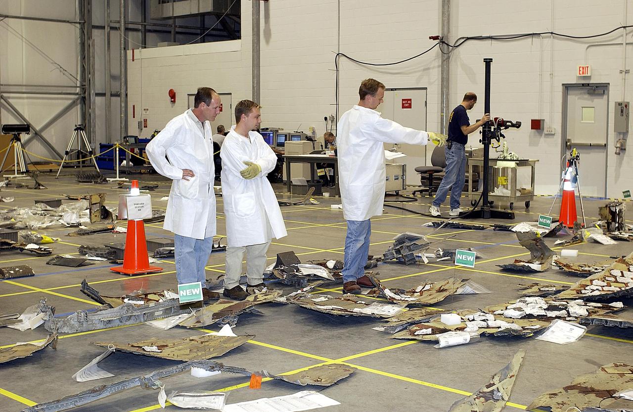 KENNEDY SPACE CENTER, FLA. -  Members of the Columbia Reconstruction Project team look at new pieces of debris placed on the floor of the RLV Hangar.  The team is identifying pieces and placing them on a grid approximating the shape of the orbiter.  About 25 percent of the orbiter has been delivered to the hangar.