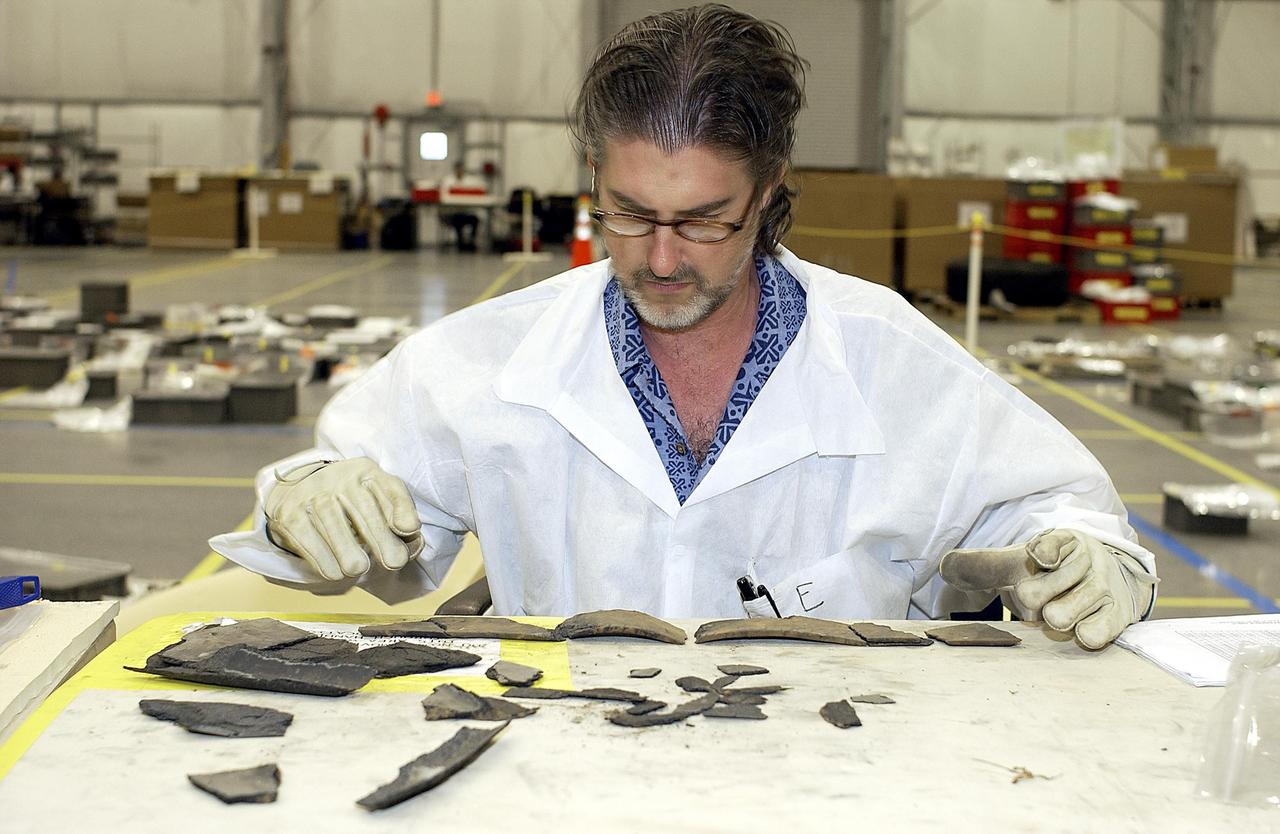 KENNEDY SPACE CENTER, FLA. -  A member of the Columbia Reconstruction Project team examines small pieces of debris shipped to KSC and brought to the RLV Hangar.  The team is identifying pieces and placing them on a grid approximating the shape of the orbiter.  About 25 percent of the orbiter has been delivered to the hangar.