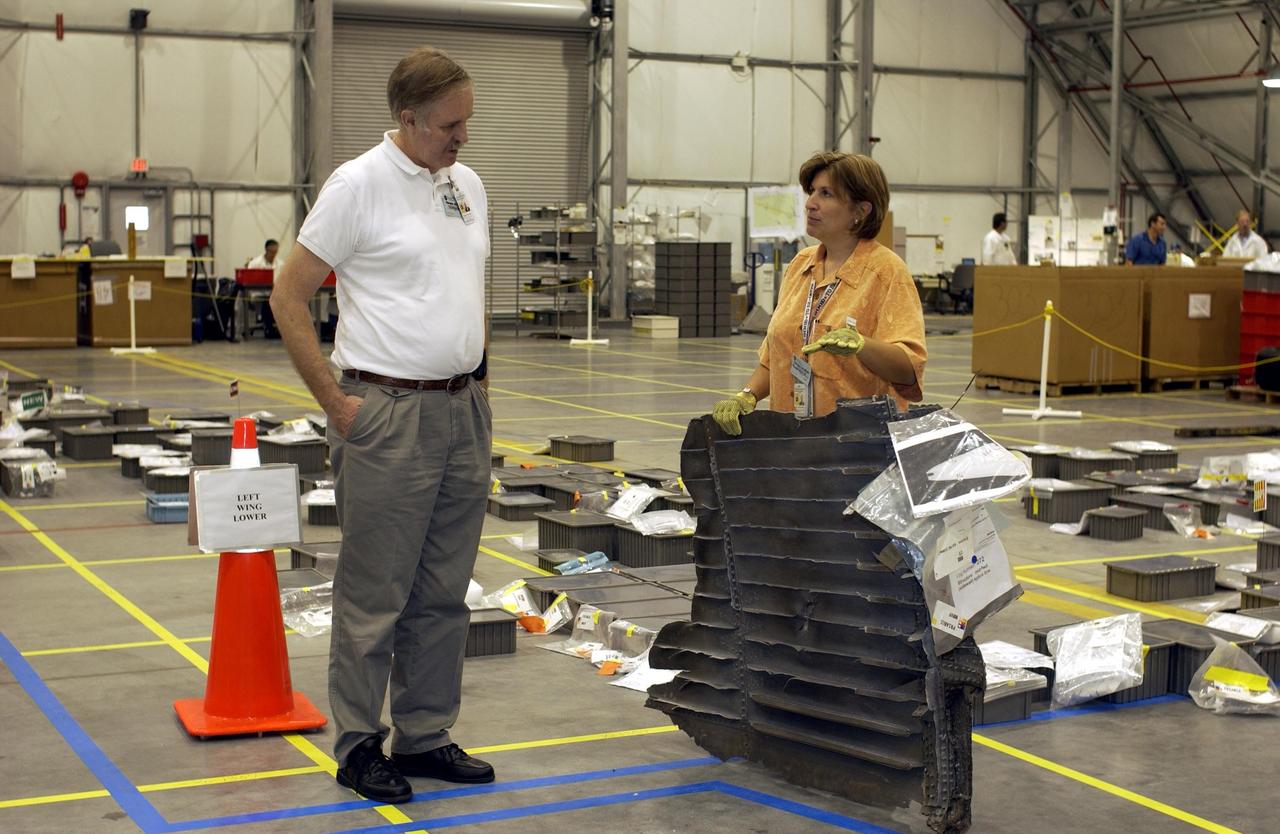 KENNEDY SPACE CENTER, FLA. -  Members of the Columbia Reconstruction Project team discuss a piece of debris on the floor of the RLV Hangar.  The team is identifying pieces and placing them on a grid approximating the shape of the orbiter.  About 25 percent of the orbiter has been delivered to the hangar.