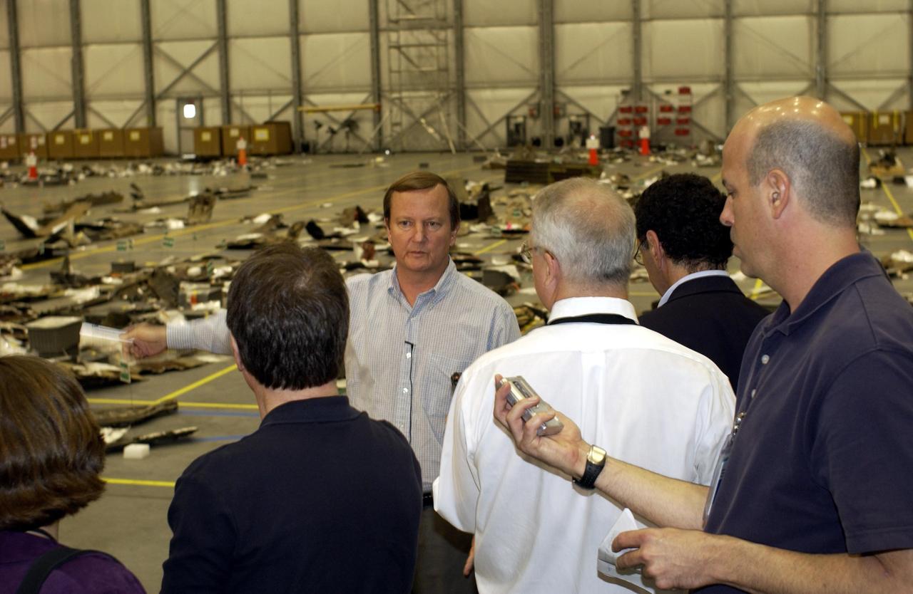 KENNEDY SPACE CENTER, FLA. -  Shuttle Launch Director Mike Leinbach answers reporters' questions in the RLV Hangar.   Leinbach is overseeing assessment of the debris, seen in the background, as it is delivered to KSC.  The Columbia Reconstruction Project team is identifying pieces and placing them on a grid approximating the shape of the orbiter.  About 25 percent of the orbiter has been delivered to the hangar.