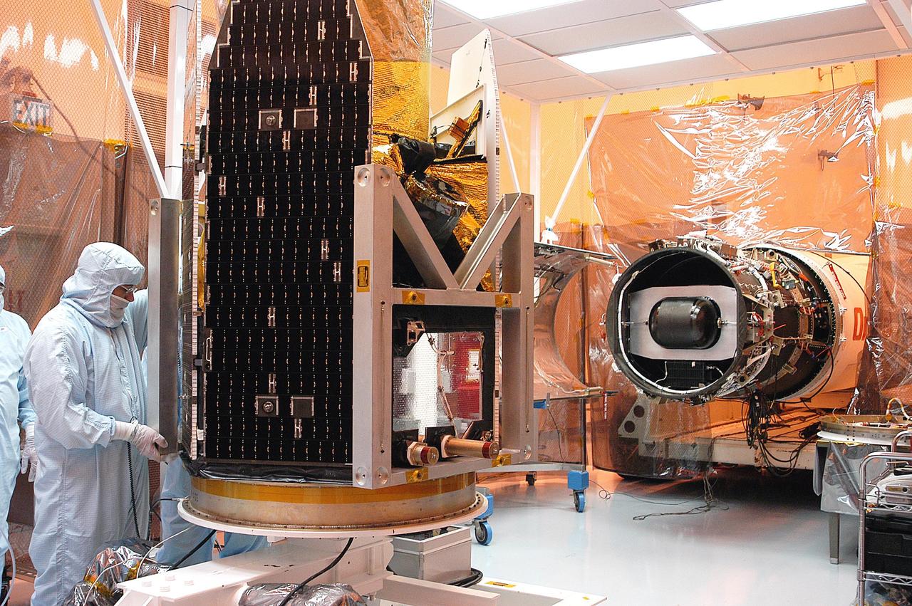 KENNEDY SPACE CENTER, FLA. -  The Galaxy Evolution Explorer (GALEX) spacecraft awaits inspection after being moved into a vertical position in the Payload Hazardous Servicing Facility.  On the right is the Pegasus launch vehicle from which it was demated. A borescope inspection will be conducted on the spacecraft to locate a small fastener and associated clip missing from a demated connector identified during preflight testing. GALEX is an orbiting space telescope that will observe galaxies in ultraviolet light across 10 billion years of cosmic history. During its 29-month mission, GALEX will produce the first comprehensive map of a Universe of galaxies under construction, bringing more understanding to how galaxies like the Milky Way were formed. The GALEX launch date in late April is currently under review.