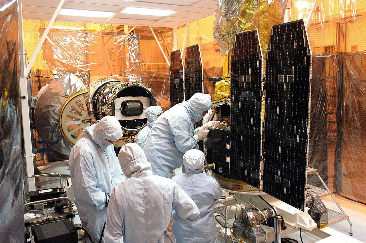 KENNEDY SPACE CENTER, FLA. - Foreign object debris shields are installed and a borescope inspection is conducted on the Galaxy Evolution Explorer (GALEX) spacecraft in the Payload Hazardous Servicing Facility. On the left is the Pegasus launch vehicle from which it was demated. Technicians are looking for a small fastener and associated clip missing from a demated connector identified during preflight testing. GALEX is an orbiting space telescope that will observe galaxies in ultraviolet light across 10 billion years of cosmic history. During its 29-month mission, GALEX will produce the first comprehensive map of a Universe of galaxies under construction, bringing more understanding to how galaxies like the Milky Way were formed. The GALEX launch date in late April is currently under review.