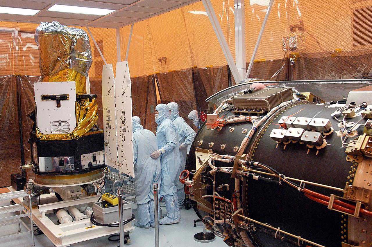 KENNEDY SPACE CENTER, FLA. - Foreign object debris shields are installed and a borescope inspection is conducted on the Galaxy Evolution Explorer (GALEX) spacecraft in the Payload Hazardous Servicing Facility. On the right is the Pegasus launch vehicle from which it was demated. Technicians are looking for a small fastener and associated clip missing from a demated connector identified during preflight testing. GALEX is an orbiting space telescope that will observe galaxies in ultraviolet light across 10 billion years of cosmic history. During its 29-month mission, GALEX will produce the first comprehensive map of a Universe of galaxies under construction, bringing more understanding to how galaxies like the Milky Way were formed. The GALEX launch date in late April is currently under review.