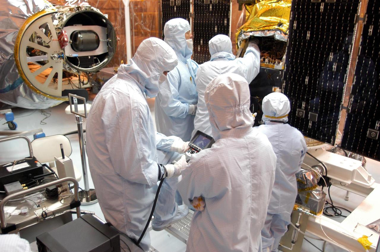 KENNEDY SPACE CENTER, FLA. - Foreign object debris shields are installed and a borescope inspection is conducted on the Galaxy Evolution Explorer (GALEX) spacecraft in the Payload Hazardous Servicing Facility. On the left is the Pegasus launch vehicle from which it was demated. Technicians are looking for a small fastener and associated clip missing from a demated connector identified during preflight testing. GALEX is an orbiting space telescope that will observe galaxies in ultraviolet light across 10 billion years of cosmic history. During its 29-month mission, GALEX will produce the first comprehensive map of a Universe of galaxies under construction, bringing more understanding to how galaxies like the Milky Way were formed. The GALEX launch date in late April is currently under review.