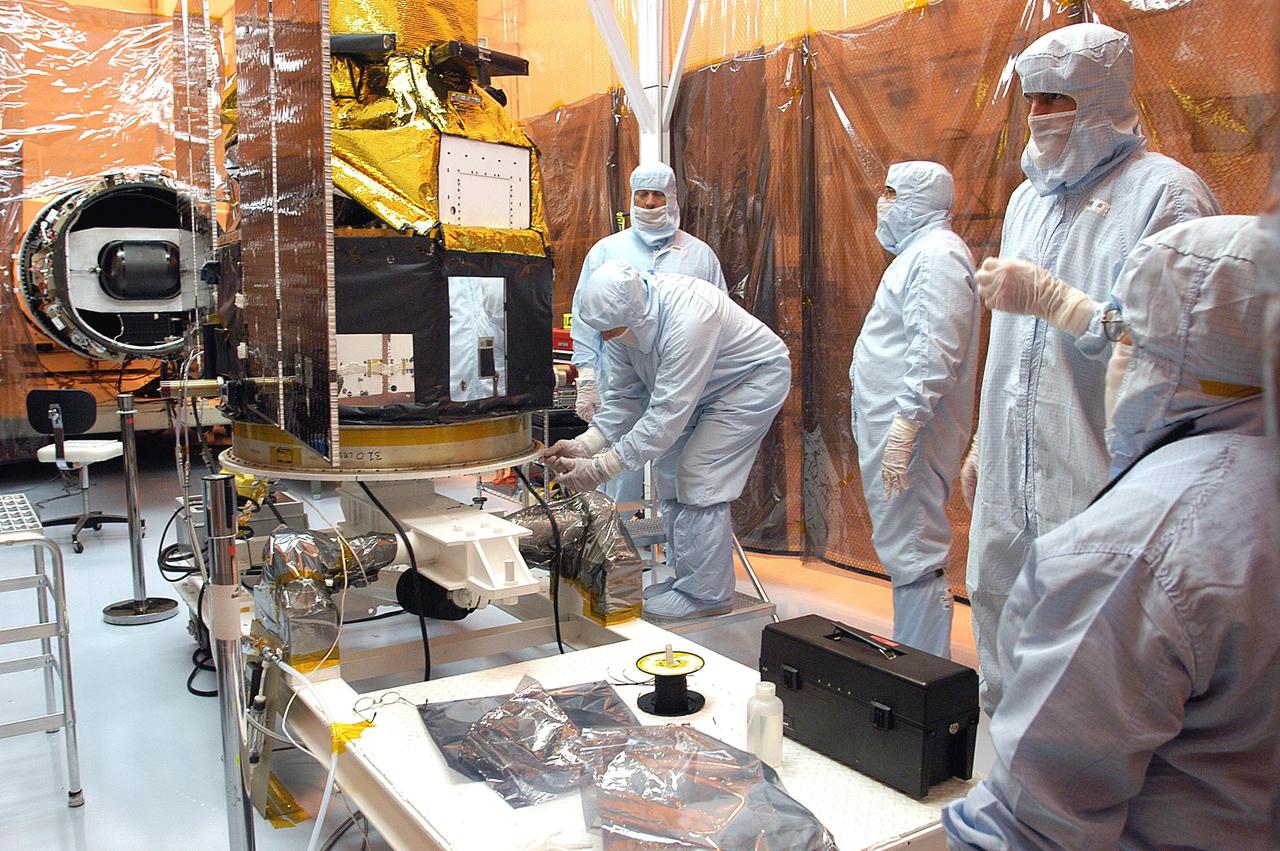 KENNEDY SPACE CENTER, FLA. -  Foreign object debris shields are installed and a borescope inspection is conducted on the Galaxy Evolution Explorer (GALEX) spacecraft in the Payload Hazardous Servicing Facility. Technicians are looking for a small fastener and associated clip missing from a demated connector identified during preflight testing. On the left is the Pegasus launch vehicle from which the spacecraft was demated. GALEX is an orbiting space telescope that will observe galaxies in ultraviolet light across 10 billion years of cosmic history. During its 29-month mission, GALEX will produce the first comprehensive map of a Universe of galaxies under construction, bringing more understanding to how galaxies like the Milky Way were formed. The GALEX launch date in late April is currently under review.