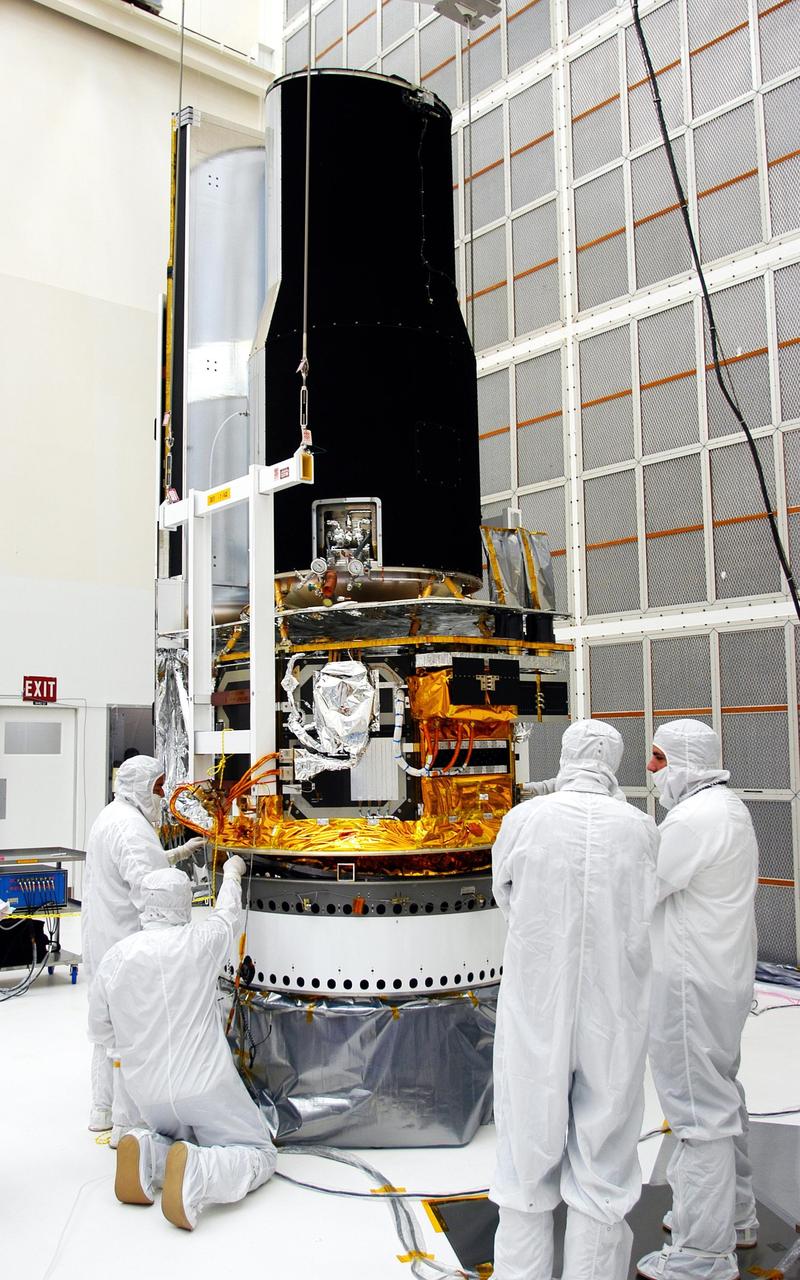 KENNEDY SPACE CENTER, FLA. - Workers in Building AE check the fitting of the Space Infrared Telescope Facility (SIRTF) with the payload attach fitting beneath. SIRTF will be mated with its Delta II launch vehicle via the fitting. SIRTF is currently scheduled for transportation to Launch Complex 17-B, Cape Canaveral Air Force Station, and hoisting atop the Delta II on or about April 4.