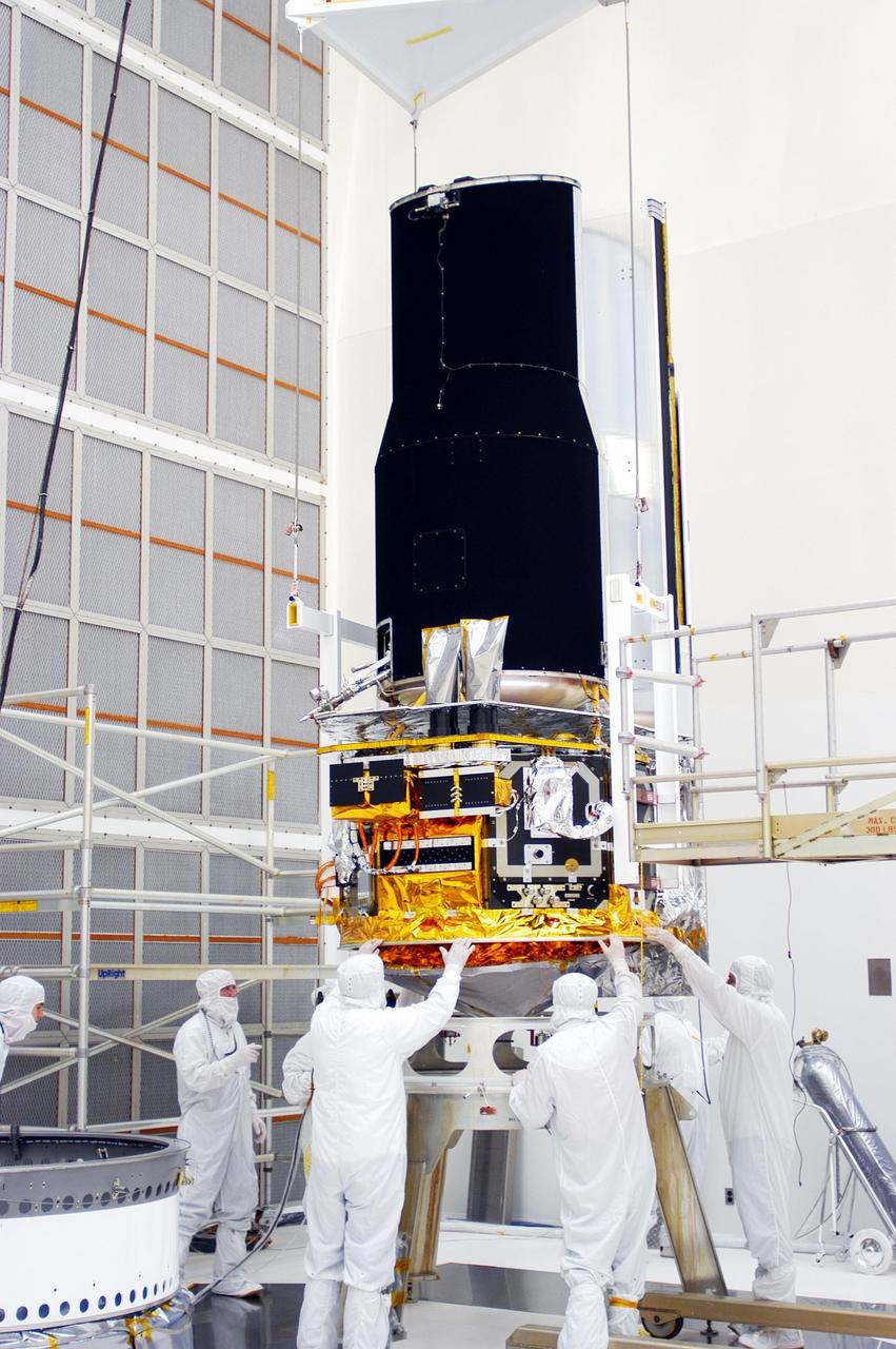KENNEDY SPACE CENTER, FLA. - Workers in Building AE work on the Space Infrared Telescope Facility (SIRTF). The telescope will be mated with its Delta II launch vehicle via the payload attach fitting seen at left. SIRTF is currently scheduled for transportation to Launch Complex 17-B, Cape Canaveral Air Force Station, and hoisting atop the Delta II on or about April 4.