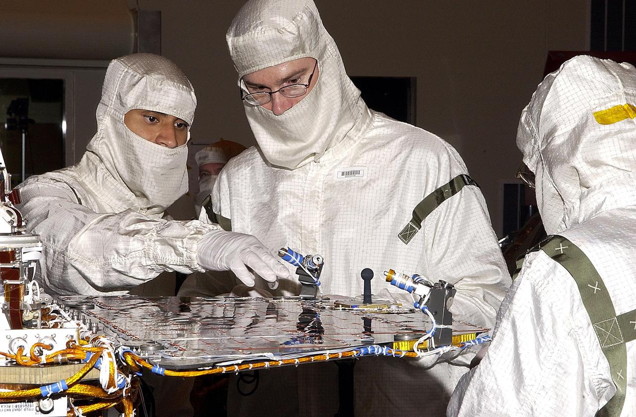 KENNEDY SPACE CENTER, FLA. -  Workers discuss a point of interest on one solar panel of the Mars Exploration Rover 2 (MER-2) before flight stow.  Set to launch in Spring 2003, the MER Mission will consist of two identical rovers designed to cover roughly 110 yards each Martian day over various terrain. The rovers will be identical to each other, but will land at different regions of Mars.  Each rover will carry five scientific instruments that will allow it to search for evidence of liquid water that may have been present in the planet's past.  The first rover has a launch window opening May 30, and the second rover a window opening June 25.