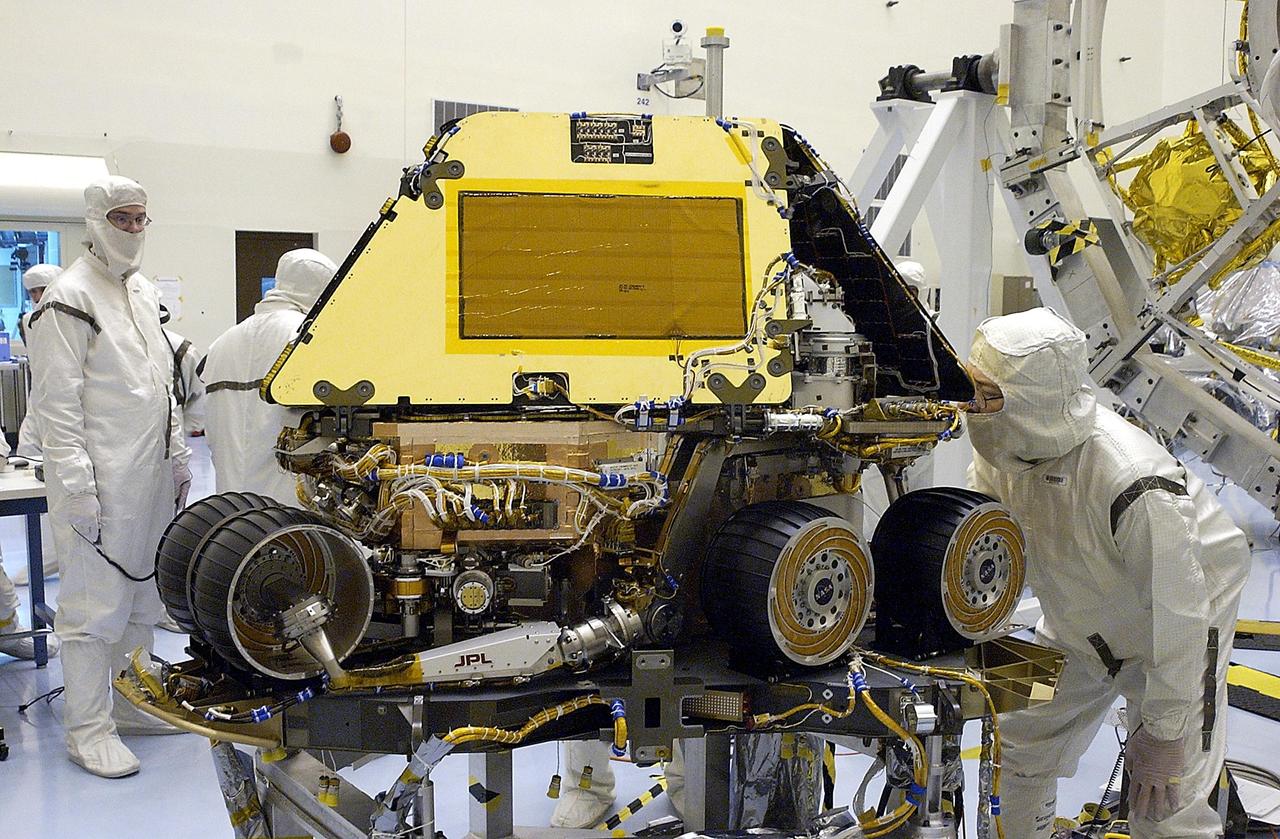 KENNEDY SPACE CENTER, FLA. -  After closing the solar panels for flight stow, workers examine the Mars Exploration Rover 2 (MER-2).   Set to launch in Spring 2003, the MER Mission will consist of two identical rovers designed to cover roughly 110 yards each Martian day over various terrain. The rovers will be identical to each other, but will land at different regions of Mars.  Each rover will carry five scientific instruments that will allow it to search for evidence of liquid water that may have been present in the planet's past.  The first rover has a launch window opening May 30, and the second rover a window opening June 25.