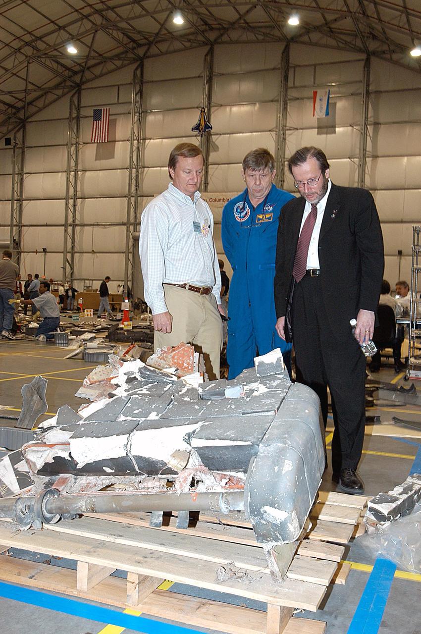 KENNEDY SPACE CENTER, FLA. - In the RLV Hangar at KSC, Shuttle Launch Director Mike Leinbach (left) shows some of the debris from Space Shuttle Columbia to former payload specialist Dr. Roger Crouch (center) and NASA Chief of Staff and White House liaison Courtney Stadd.  The search of more than 500,000 acres of primary recovery area for Columbia material has passed the halfway mark.  To date about 28 percent of Columbia, by weight, has been delivered to the hangar.