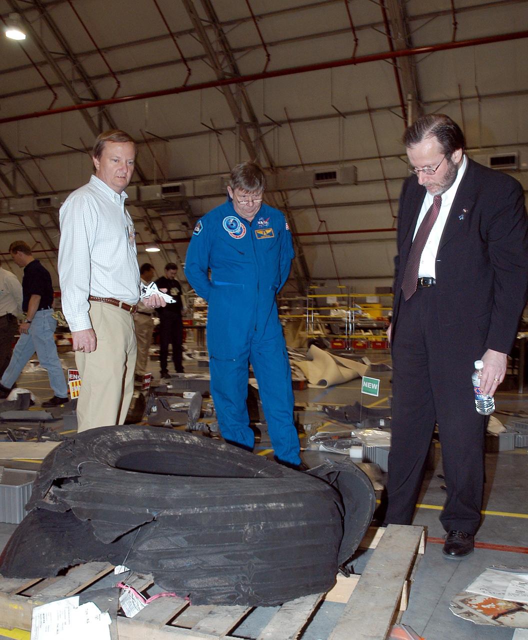 KENNEDY SPACE CENTER, FLA. -  In the RLV Hangar at KSC, Shuttle Launch Director Mike Leinbach (left), former payload specialist Dr. Roger Crouch (center) and NASA Chief of Staff and White House liaison Courtney Stadd look at one of Space Shuttle Columbia's tires. The debris is one of more than 35,000 pieces collected so far.  More than 1,218 pieces have been identified. The search of more than 500,000 acres of primary recovery area for Columbia material has passed the halfway mark.  To date about 28 percent of Columbia, by weight, has been delivered to the hangar.