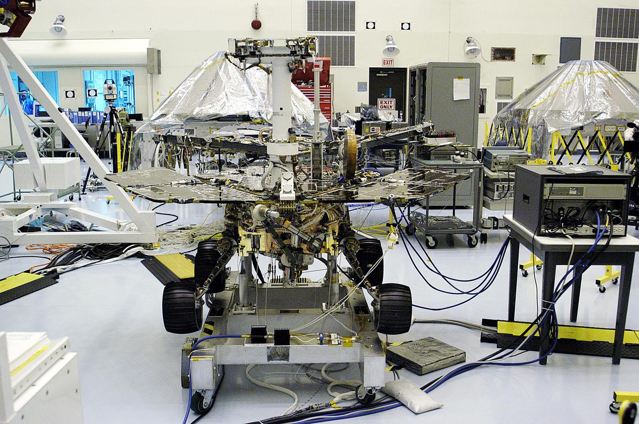 KENNEDY SPACE CENTER, FLA. - The Mars Exploration Rover 1 (MER-1) is seen in the foreground after the science boom was deployed.  Set to launch in Spring 2003, the MER Mission will consist of two identical rovers designed to cover roughly 110 yards each Martian day over various terrain. Each rover will carry five scientific instruments that will allow it to search for evidence of liquid water that may have been present in the planet's past.  The rovers will be identical to each other, but will land at different regions of Mars.  The first rover has a launch window opening May 30, and the second rover a window opening June 25.