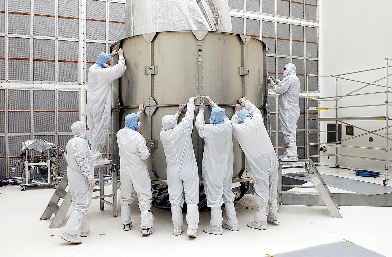 KENNEDY SPACE CENTER, FLA. - Workers adjust a second layer of the payload canister around the Space Infrared Telescope Facility (SIRTF) in the background.  SIRTF is currently scheduled for transportation to Launch Complex 17-B, Cape Canaveral Air Force Station, and mating with the Delta II on or about April 4.