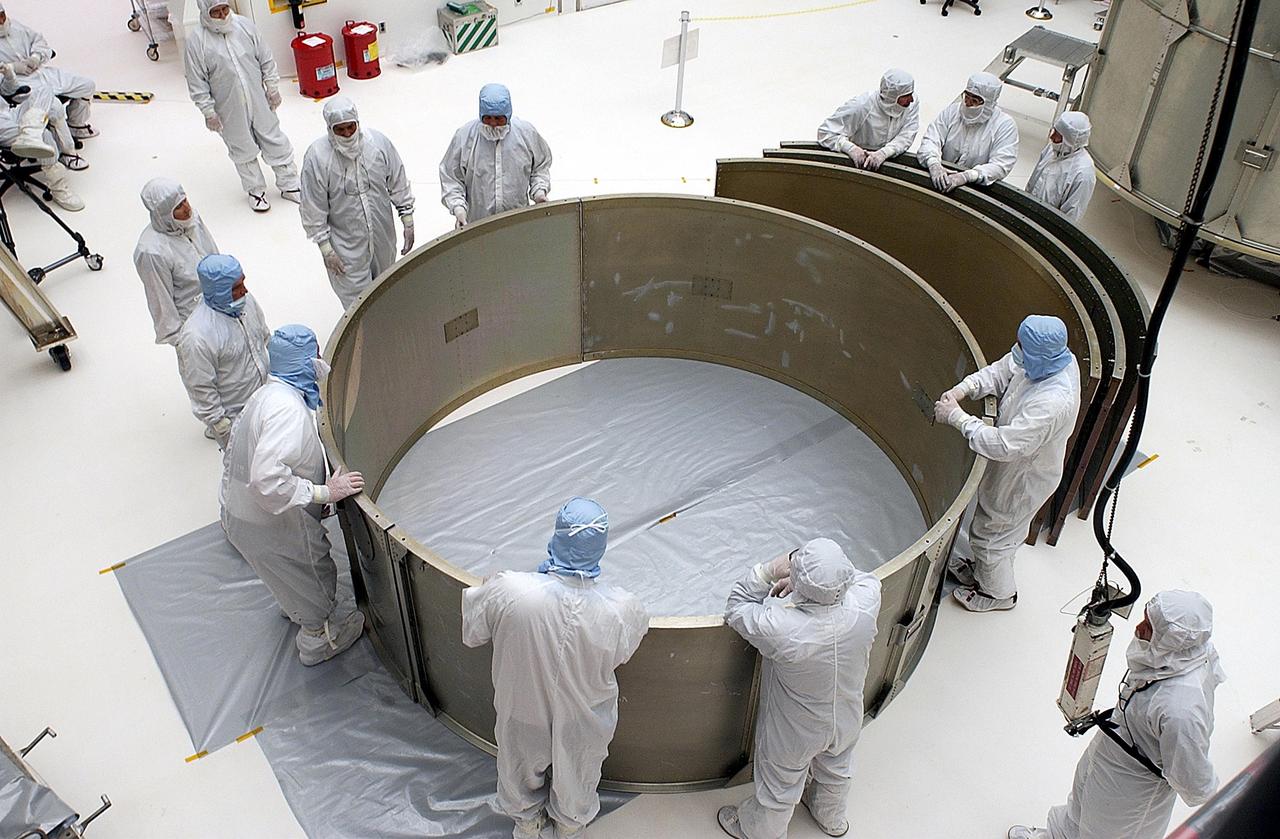 KENNEDY SPACE CENTER, FLA. - Workers assemble on the floor the top ring for the payload canister before attaching it to the third ring and installing them over the Space Infrared Telescope Facility (SIRTF). SIRTF is currently scheduled for transportation to Launch Complex 17-B, Cape Canaveral Air Force Station, and mating with the Delta II on or about April 4.