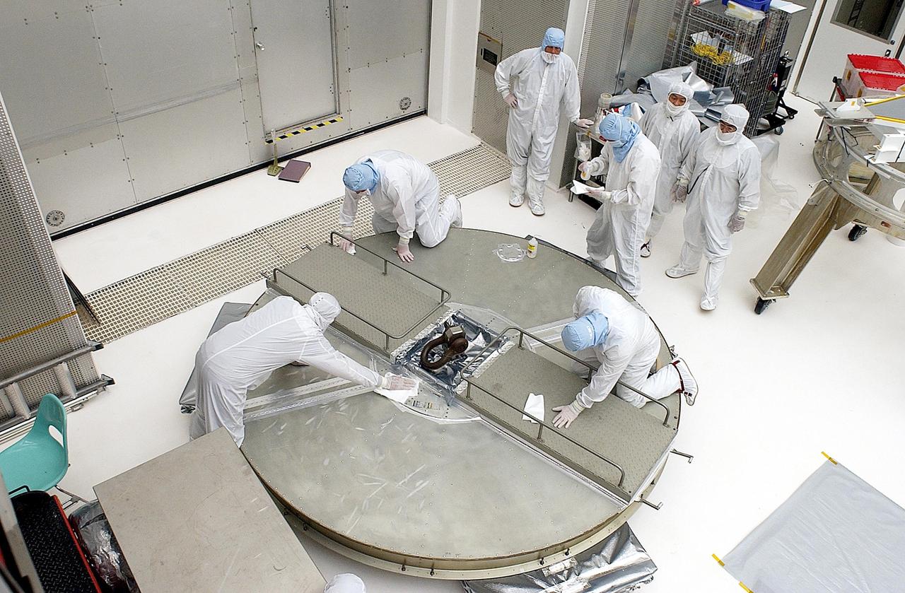 KENNEDY SPACE CENTER, FLA. - Workers complete assembling the top ring for the payload canister before attaching to the third ring and installing them over the Space Infrared Telescope Facility (SIRTF). SIRTF is currently scheduled for transportation to Launch Complex 17-B, Cape Canaveral Air Force Station, and mating with the Delta II on or about April 4.