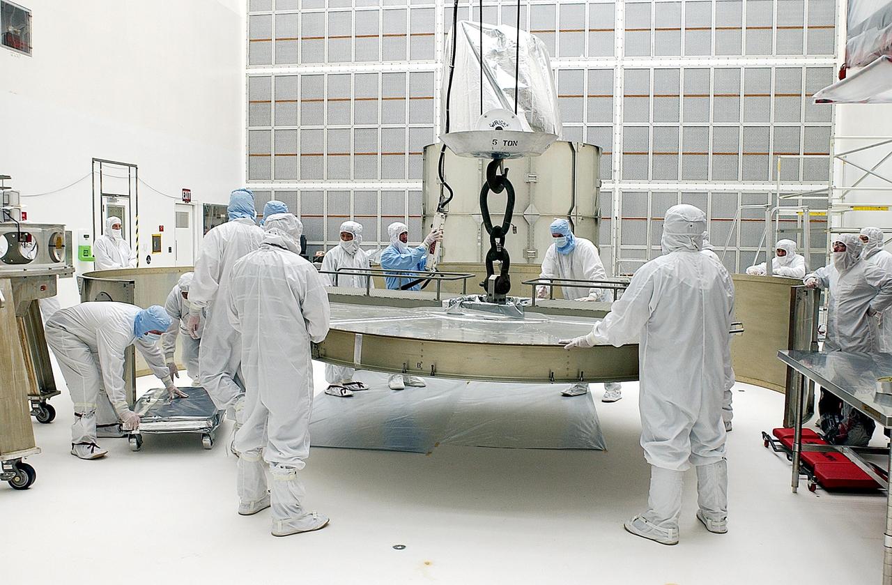 KENNEDY SPACE CENTER, FLA. - Workers attach a crane to the top ring on the payload canister. They will lift the top and attach the third ring before installing them over the Space Infrared Telescope Facility (SIRTF). SIRTF is currently scheduled for transportation to Launch Complex 17-B, Cape Canaveral Air Force Station, and mating with the Delta II on or about April 4.
