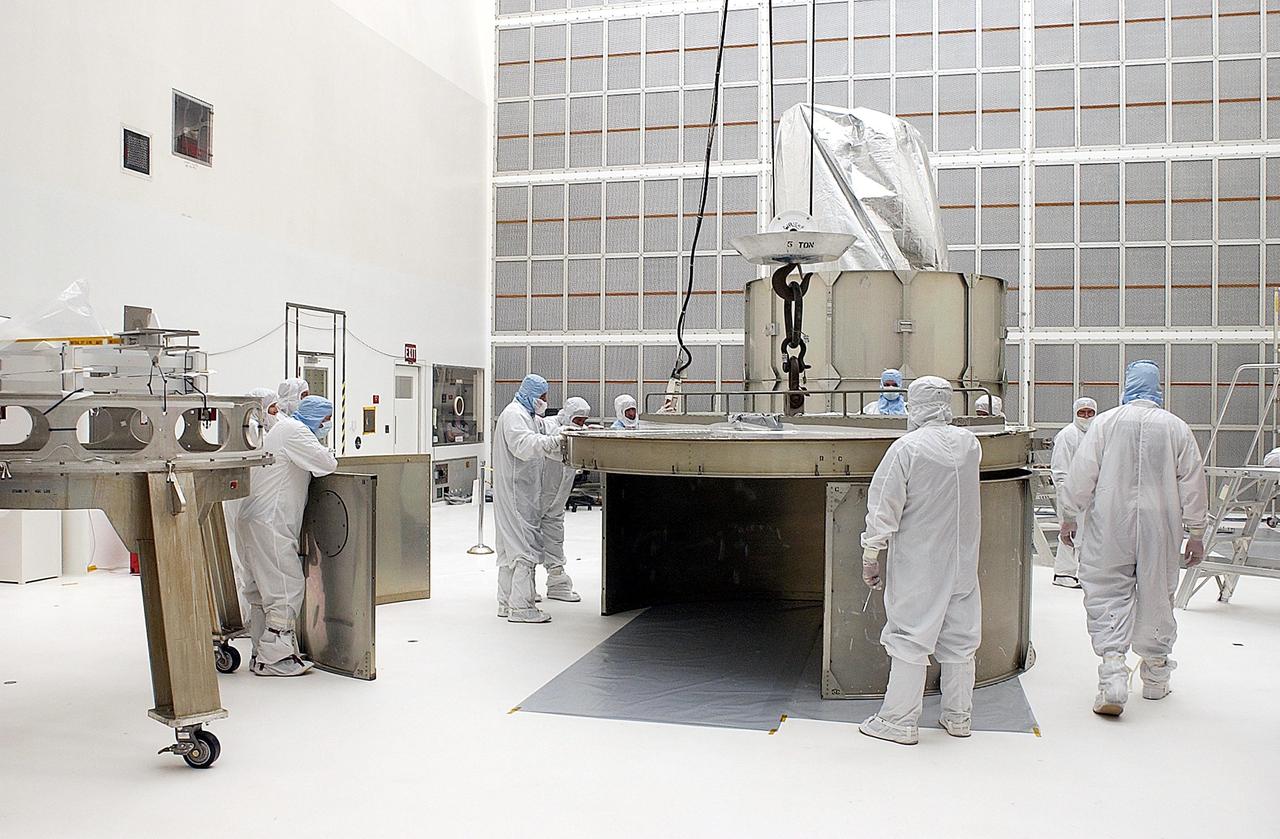KENNEDY SPACE CENTER, FLA. -- Workers adjust the top ring on the payload canister before installing over the Space Infrared Telescope Facility (SIRTF). SIRTF is currently scheduled for transportation to Launch Complex 17-B, Cape Canaveral Air Force Station, and mating with the Delta II on or about April 4.