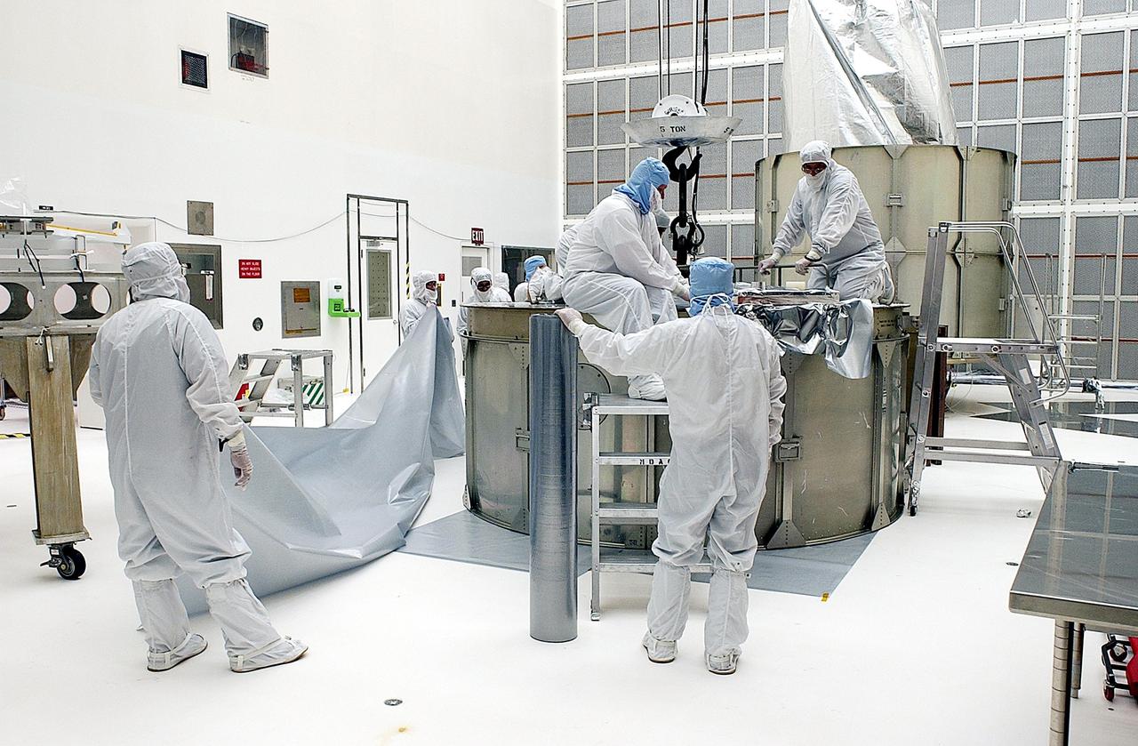 KENNEDY SPACE CENTER, FLA. -- Workers adjust the top ring on the payload canister before installing over the Space Infrared Telescope Facility (SIRTF). SIRTF is currently scheduled for transportation to Launch Complex 17-B, Cape Canaveral Air Force Station, and mating with the Delta II on or about April 4.