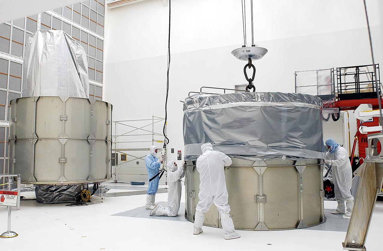 KENNEDY SPACE CENTER, FLA. -- Workers adjust a cover on the top two rings to be installed over the Space Infrared Telescope Facility (SIRTF). SIRTF is currently scheduled for transportation to Launch Complex 17-B, Cape Canaveral Air Force Station, and mating with the Delta II on or about April 4.