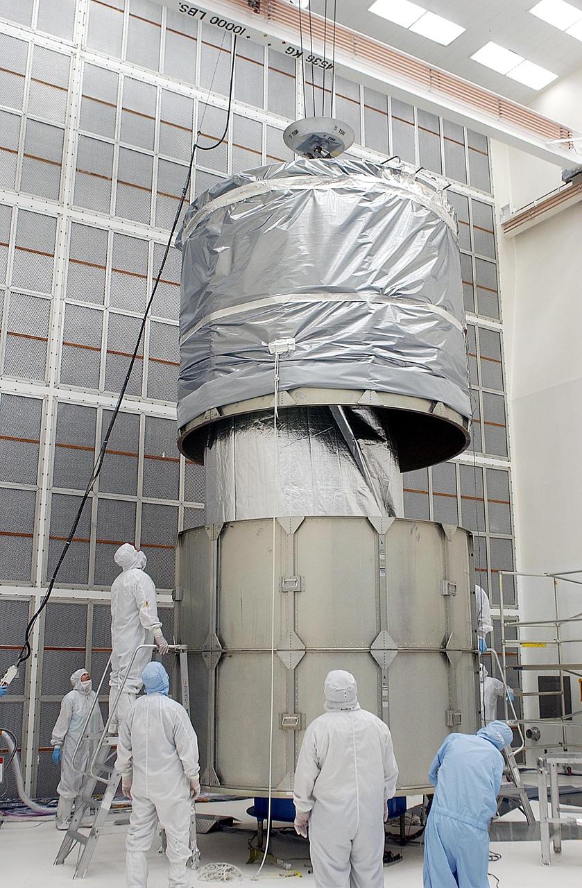 KENNEDY SPACE CENTER, FLA. -- Workers lower the top rings of the payload canister over the Space Infrared Telescope Facility (SIRTF) below. After installation, SIRTF will be transported to Launch Complex 17-B, Cape Canaveral Air Force Station, and mating with the Delta II on or about April 4.