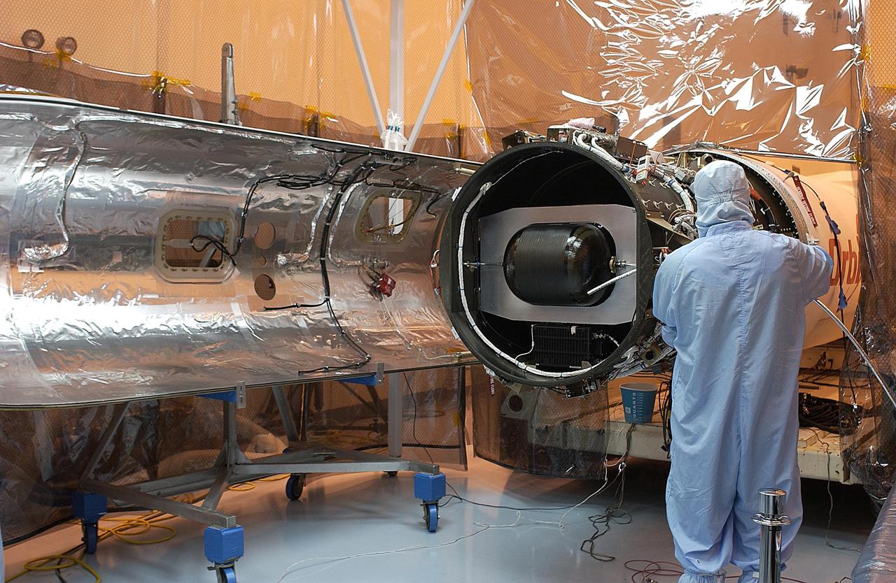 KENNEDY SPACE CENTER, FLA. - Workers prepare the Pegasus XL launch vehicle for re-mate with the Galaxy Evolution Explorer (GALEX) spacecraft. The March 26 launch was delayed to enable protective covers to be added to the Optical Wheel Assembly (OWA) on GALEX to avoid the possibility of a missing electrical cable fastener floating into and jamming the mechanism when GALEX is in orbit. Launch of GALEX is now scheduled for no earlier than April 26.
