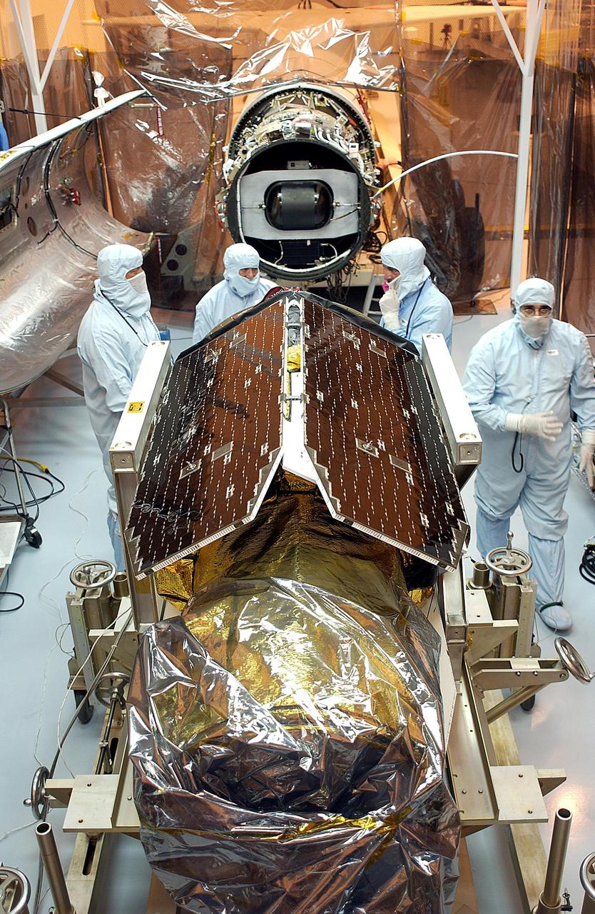 KENNEDY SPACE CENTER, FLA. - Workers prepare the Galaxy Evolution Explorer (GALEX) spacecraft for re-mate with the Pegasus XL launch vehicle. The March 26 launch was delayed to enable protective covers to be added to the Optical Wheel Assembly (OWA) to avoid the possibility of a missing electrical cable fastener floating into and jamming the mechanism when GALEX is in orbit. Launch of GALEX is now scheduled for no earlier than April 26.