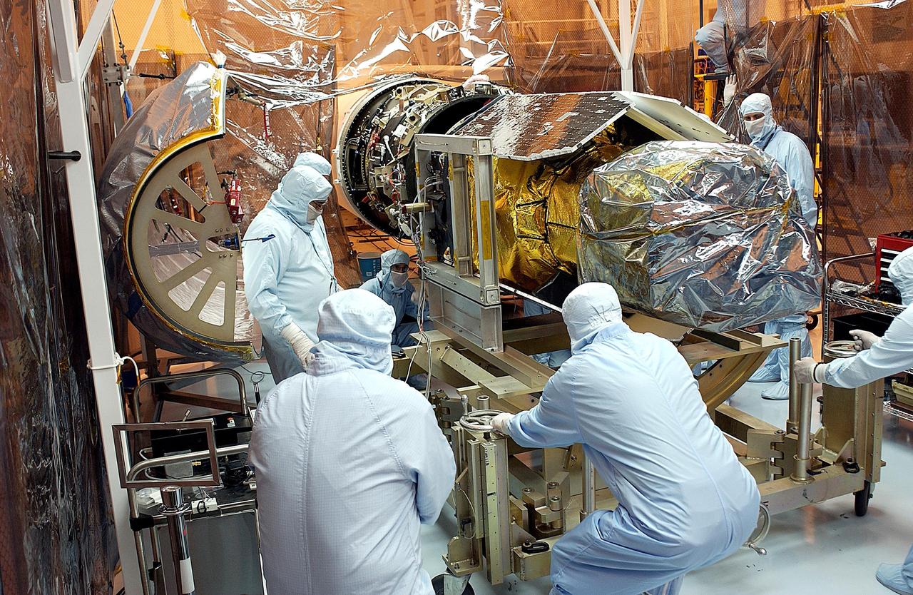 KENNEDY SPACE CENTER, FLA. -- Workers push the Galaxy Evolution Explorer (GALEX) spacecraft toward the Pegasus XL launch vehicle for a second mating. The March 26 launch was delayed to enable protective covers to be added to the Optical Wheel Assembly (OWA) on GALEX to avoid the possibility of a missing electrical cable fastener floating into and jamming the mechanism when GALEX is in orbit. Launch of GALEX is now scheduled for no earlier than April 26.