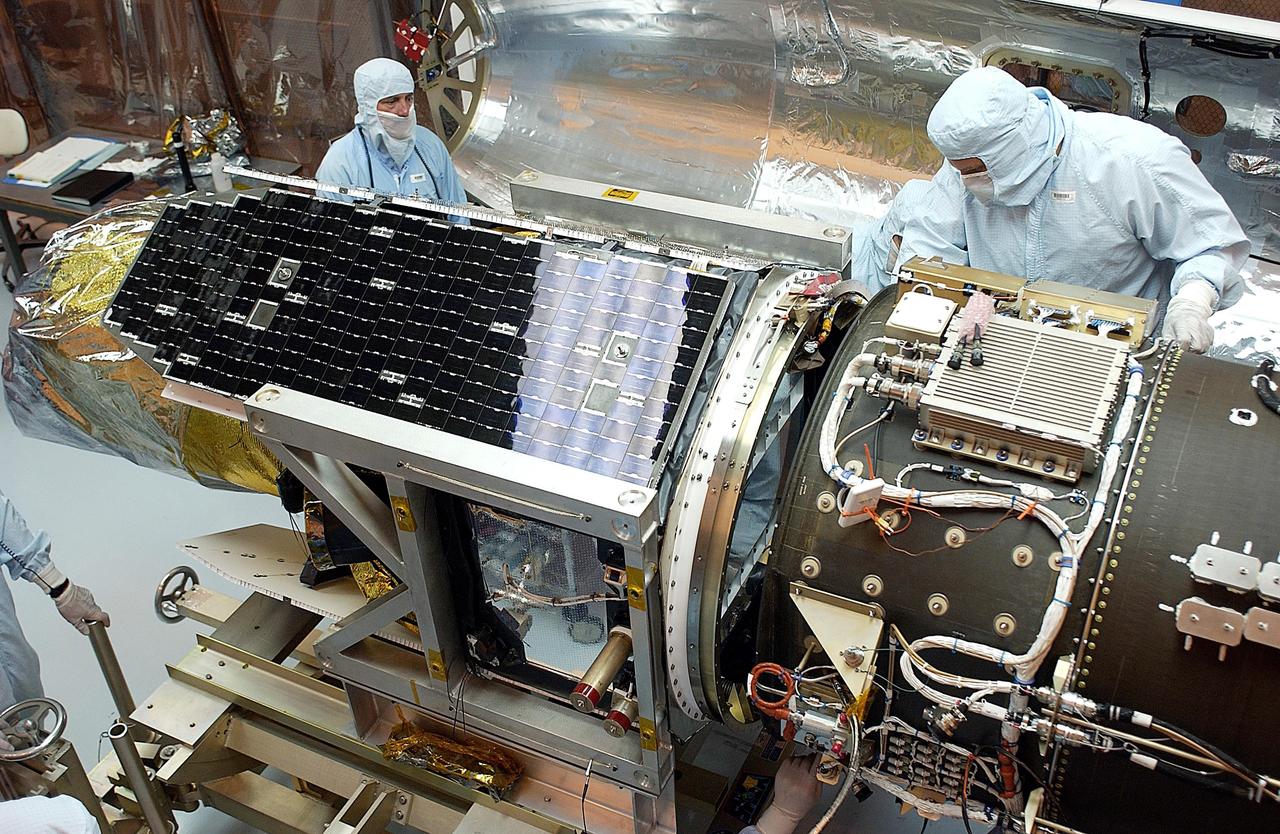 KENNEDY SPACE CENTER, FLA. -- Workers make adjustments on the Galaxy Evolution Explorer (GALEX) spacecraft during the second mating with the Pegasus XL launch vehicle. The March 26 launch was delayed to enable protective covers to be added to the Optical Wheel Assembly (OWA) on GALEX to avoid the possibility of a missing electrical cable fastener floating into and jamming the mechanism when GALEX is in orbit. Launch of GALEX is now scheduled for no earlier than April 26.