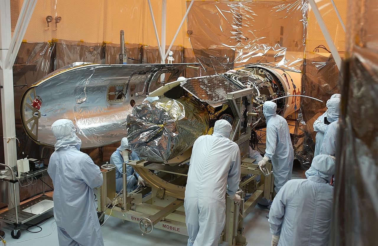 KENNEDY SPACE CENTER, FLA. -- Workers make adjustments on the Galaxy Evolution Explorer (GALEX) spacecraft during the second mating with the Pegasus XL launch vehicle. The March 26 launch was delayed to enable protective covers to be added to the Optical Wheel Assembly (OWA) on GALEX to avoid the possibility of a missing electrical cable fastener floating into and jamming the mechanism when GALEX is in orbit. Launch of GALEX is now scheduled for no earlier than April 26.