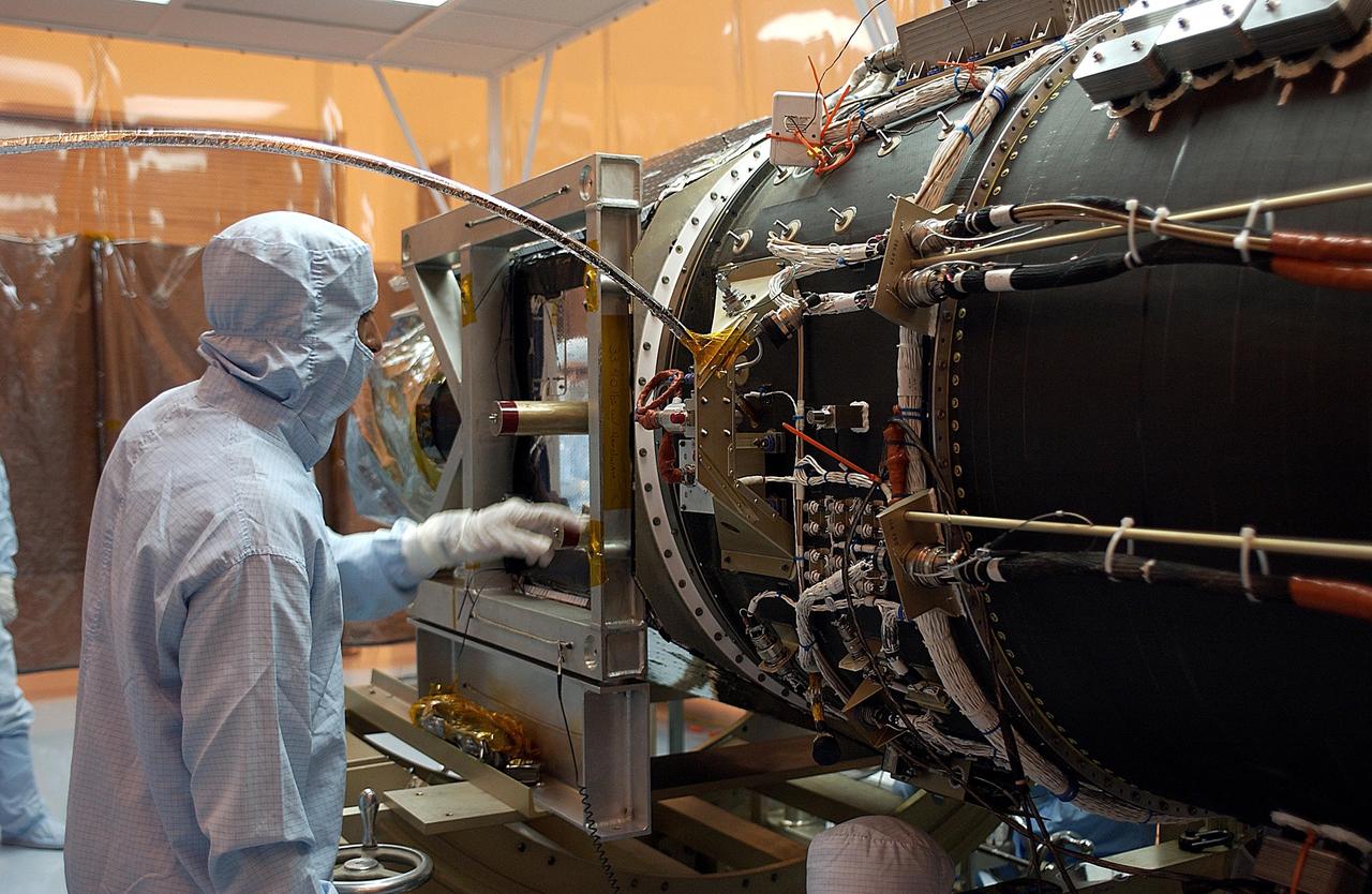 KENNEDY SPACE CENTER, FLA. - A worker makes adjustments on the Galaxy Evolution Explorer (GALEX) spacecraft during the second mating with the Pegasus XL launch vehicle. The March 26 launch was delayed to enable protective covers to be added to the Optical Wheel Assembly (OWA) on GALEX to avoid the possibility of a missing electrical cable fastener floating into and jamming the mechanism when GALEX is in orbit. Launch of GALEX is now scheduled for no earlier than April 26.
