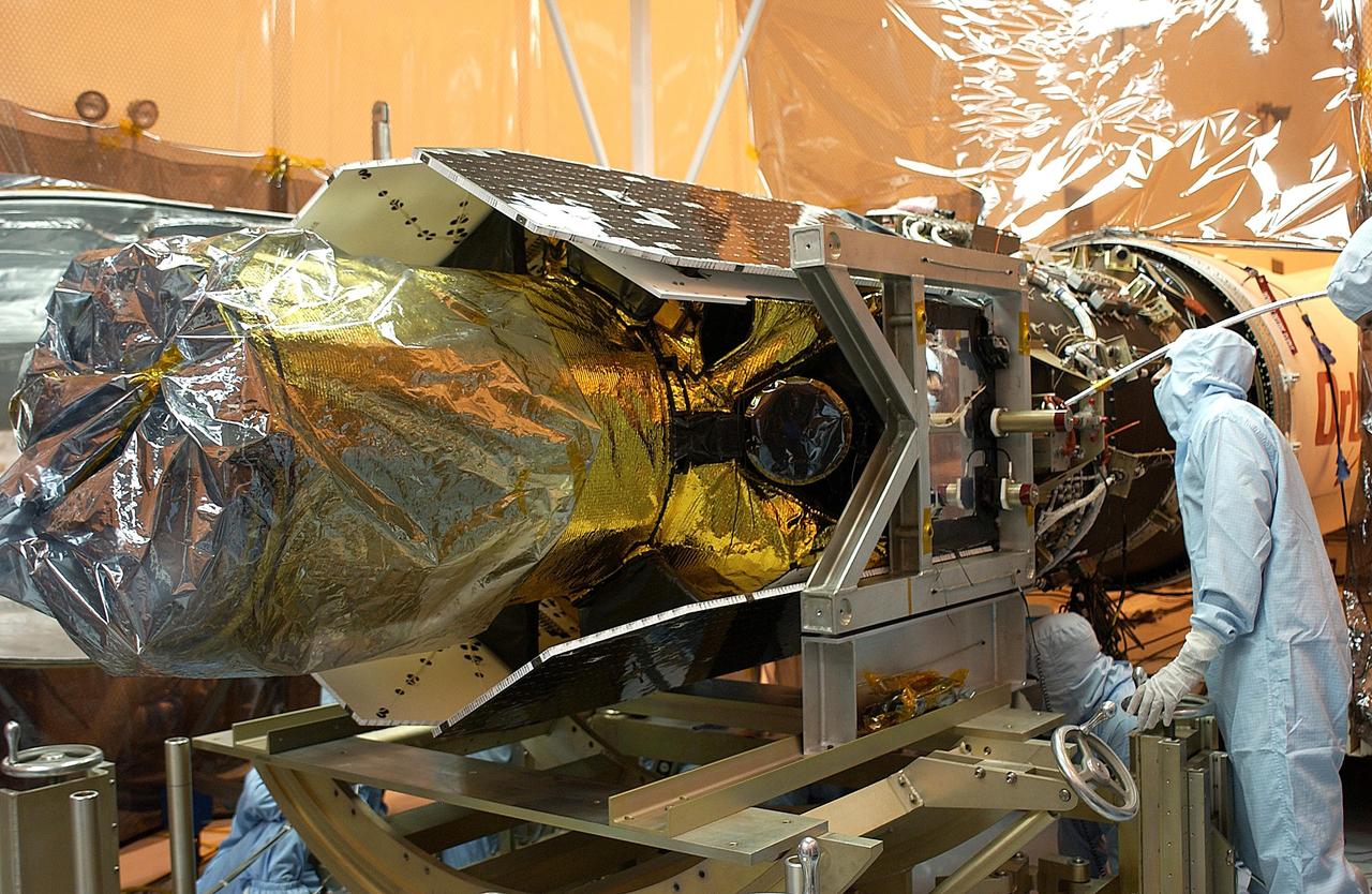 KENNEDY SPACE CENTER, FLA. -- A worker makes adjustments on the Galaxy Evolution Explorer (GALEX) spacecraft during the second mating with the Pegasus XL launch vehicle. The March 26 launch was delayed to enable protective covers to be added to the Optical Wheel Assembly (OWA) on GALEX to avoid the possibility of a missing electrical cable fastener floating into and jamming the mechanism when GALEX is in orbit. Launch of GALEX is now scheduled for no earlier than April 26. .