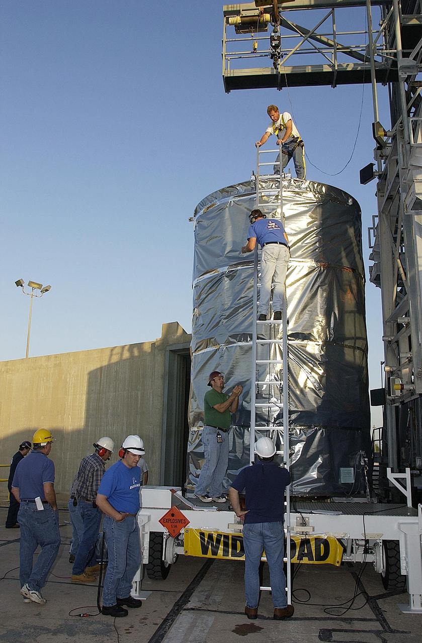 KENNEDY SPACE CENTER, FLA. -- The payload canister with the Space Infrared Telescope Facility (SIRTF) inside is lifted off the transporter on Launch Complex 17-B, Cape Canaveral Air Force Station.   SIRTF will be mated with the Delta II launch vehicle in the tower. SIRTF will obtain images and spectra by detecting the infrared energy, or heat, radiated by objects in space. Most of this infrared radiation is blocked by the Earth's atmosphere and cannot be observed from the ground. Consisting of an 0.85-meter telescope and three cryogenically cooled science instruments, SIRTF is one of NASA's largest infrared telescopes to be launched.