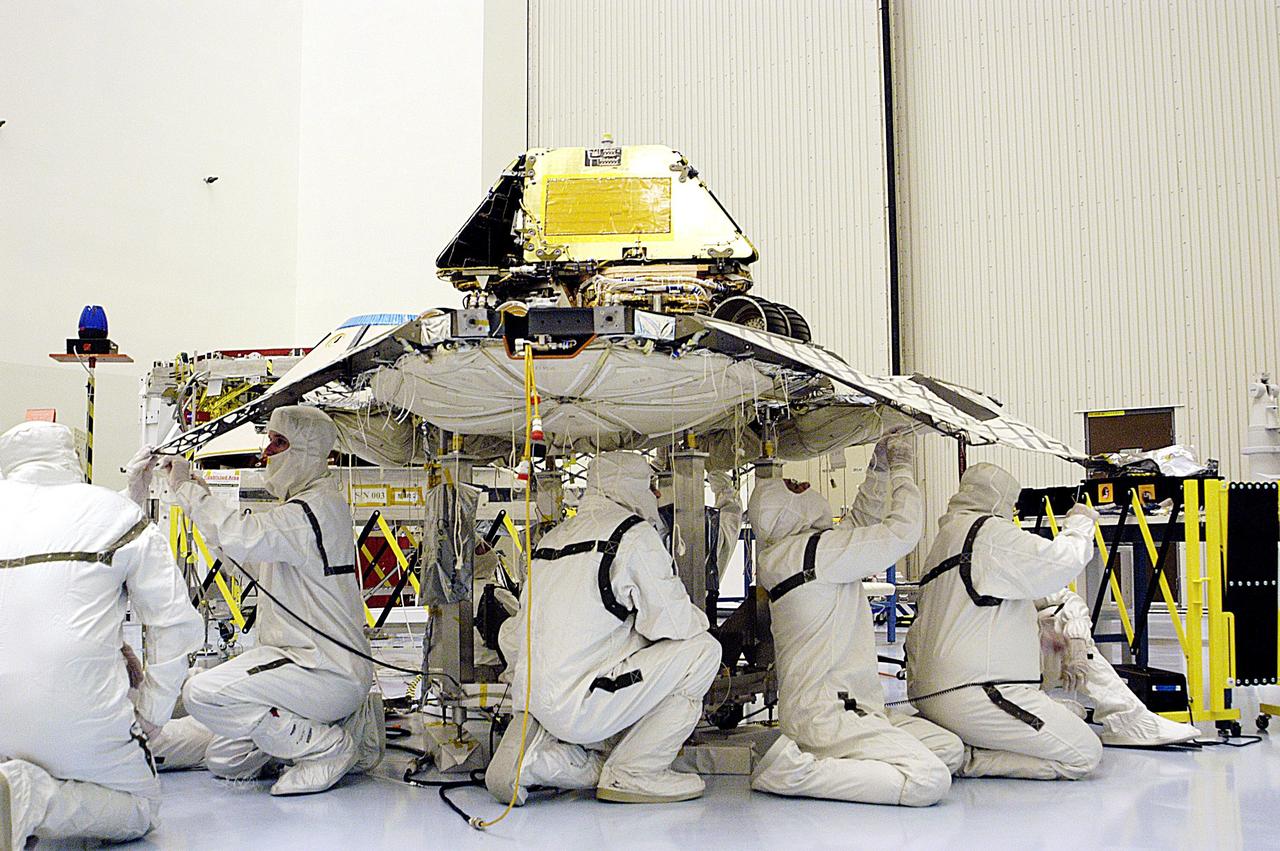 KENNEDY SPACE CENTER, FLA. -- In the Payload Hazardous Servicing Facility, technicians prepare to close the lander petals and attached airbags of the Mars Exploration Rover 2 (MER-2) around the spacecraft prior to launch. The MER Mission consists of two identical rovers set to launch in Spring 2003. Landing at different regions of Mars, they are designed to cover roughly 110 yards each Martian day over various terrain. Each rover will carry five scientific instruments that will allow it to search for evidence of liquid water that may have been present in the planet's past.