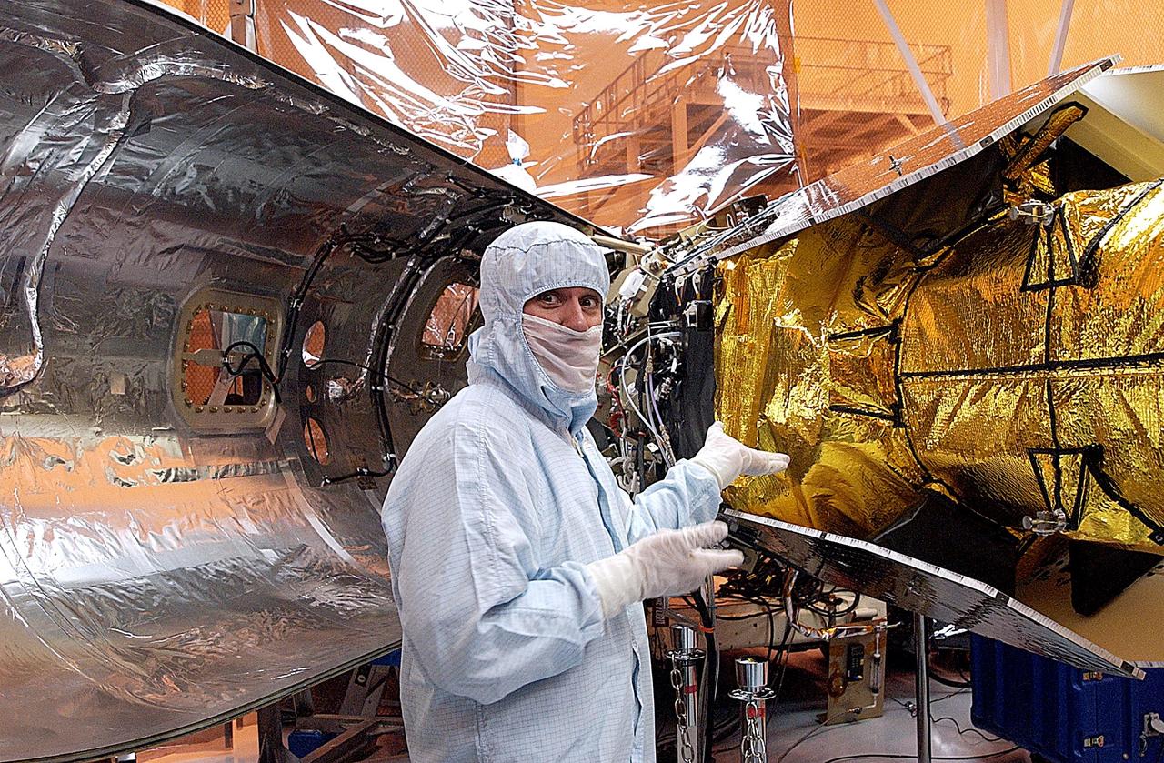 KENNEDY SPACE CENTER, FLA. --  A worker in the Multi-Payload Processing Facility gestures toward the Galaxy Evolution Explorer (GALEX) being prepared for encapsulation.  The first part of the fairing is behind him.  The spacecraft is already mated to the Pegasus launch vehicle.  After encapsulation, the GALEX/Pegasus will be transported to Cape Canaveral Air Force Station and mated to the L-1011 about four days before launch. A new launch date has not been determined.