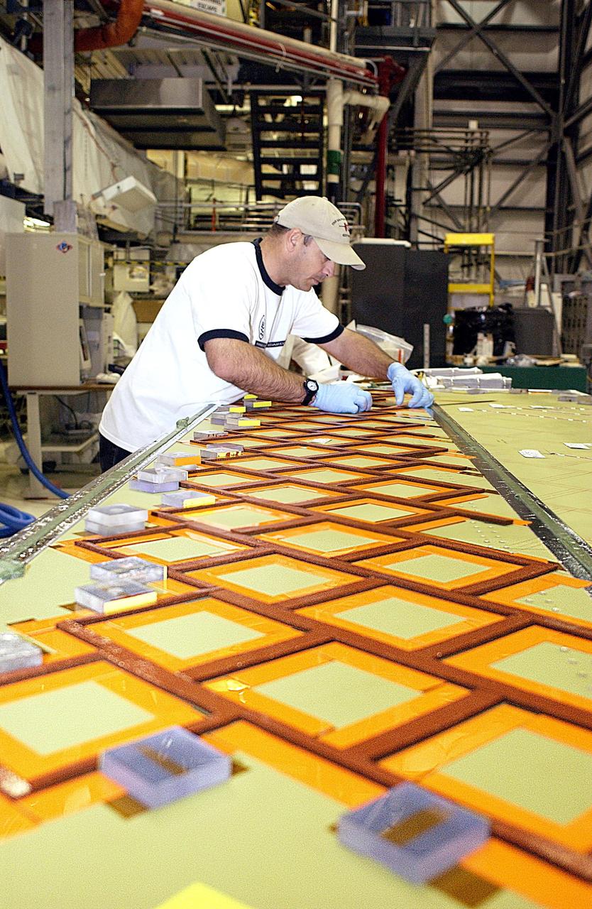 KENNEDY SPACE CENTER, FLA. -- In the Orbiter Processing Facility, United Space Alliance employee Mike Cote installs Thermal Protection System tiles on a test panel.  The test panel and sections of Space Shuttle orbiter Enterprise (OV-101) will be transferred to the Southwest Research Institute for testing after the tile installation is complete. The testing has been requested by the Columbia Accident Investigation Board. Sections of Enterprise were borrowed from the Smithsonian Institution's Air and Space Museum where the orbiter is being stored at the Washington Dulles International Airport. Enterprise was the first orbiter built in the Shuttle fleet and was used to conduct the Approach and Landing Test Program before the first powered Shuttle flight.