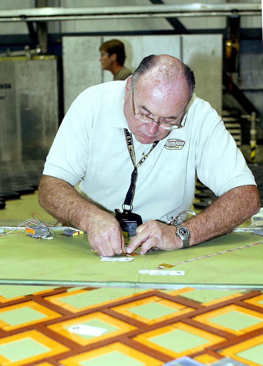 KENNEDY SPACE CENTER, FLA. -- In the Orbiter Processing Facility, an employee from The Boeing Co., Huntington Beach, Calif., installs a strain gauge on a test panel prior to installation of Thermal Protection System tile on the panel.  The test panel and sections of Space Shuttle orbiter Enterprise (OV-101) will be transferred to the Southwest Research Institute for testing after the tile installation is complete.  The testing has been requested by the Columbia Accident Investigation Board.  Sections of Enterprise   were borrowed from the Smithsonian Institution's Air and Space Museum where the orbiter is being stored at the Washington Dulles International Airport.  Enterprise was the first orbiter built in the Shuttle fleet and was used to conduct the Approach and Landing Test Program before the first powered Shuttle flight.