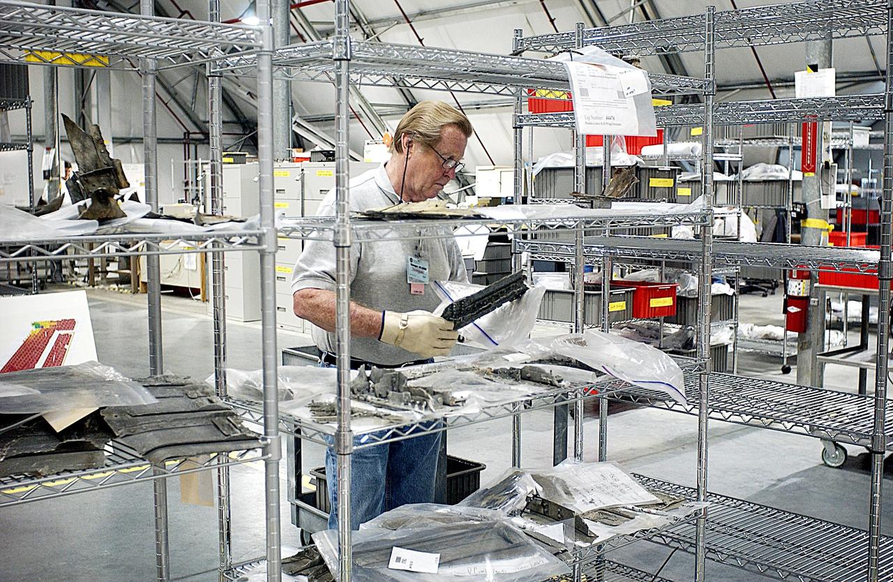 KENNEDY SPACE CENTER, FLA. -- A worker in the KSC RLV Hangar, collection site of the debris from Columbia, examines a recovered piece before bagging it. Shipped from Barksdale Air Force Base, Shreveport, La., more than 70,000 items, weighing 78,000 pounds, about 36 percent of the Shuttle by weight, have been delivered to KSC for use in the mishap investigation. Ground teams have completed 78 percent of their primary search area, and airborne crews finished 80 percent of their assigned area. Search teams have completed 98 percent of the underwater searches in Lake Nacogdoches and Toledo Bend Reservoir.
