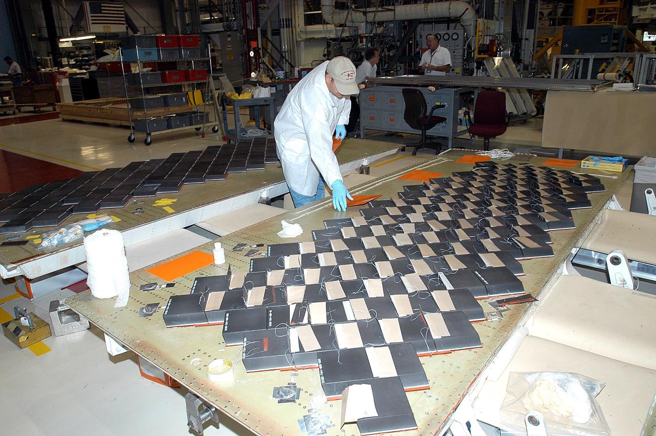KENNEDY SPACE CENTER, FLA. -- In the Orbiter Processing Facility, United Space Alliance employee Mike Cote works on installing Thermal Protection System tiles on a main landing gear door of Space Shuttle orbiter Enterprise (OV-101).  Sections of Enterprise were borrowed from the Smithsonian Institution's Air and Space Museum where the orbiter is being stored at the Washington Dulles International Airport.  Enterprise was the first orbiter built in the Shuttle fleet and was used to conduct the Approach and Landing Test Program before the first powered Shuttle flight.  After the tile installation is complete, the sections will be transferred to the Southwest Research Institute for testing requested by the Columbia Accident Investigation Board.