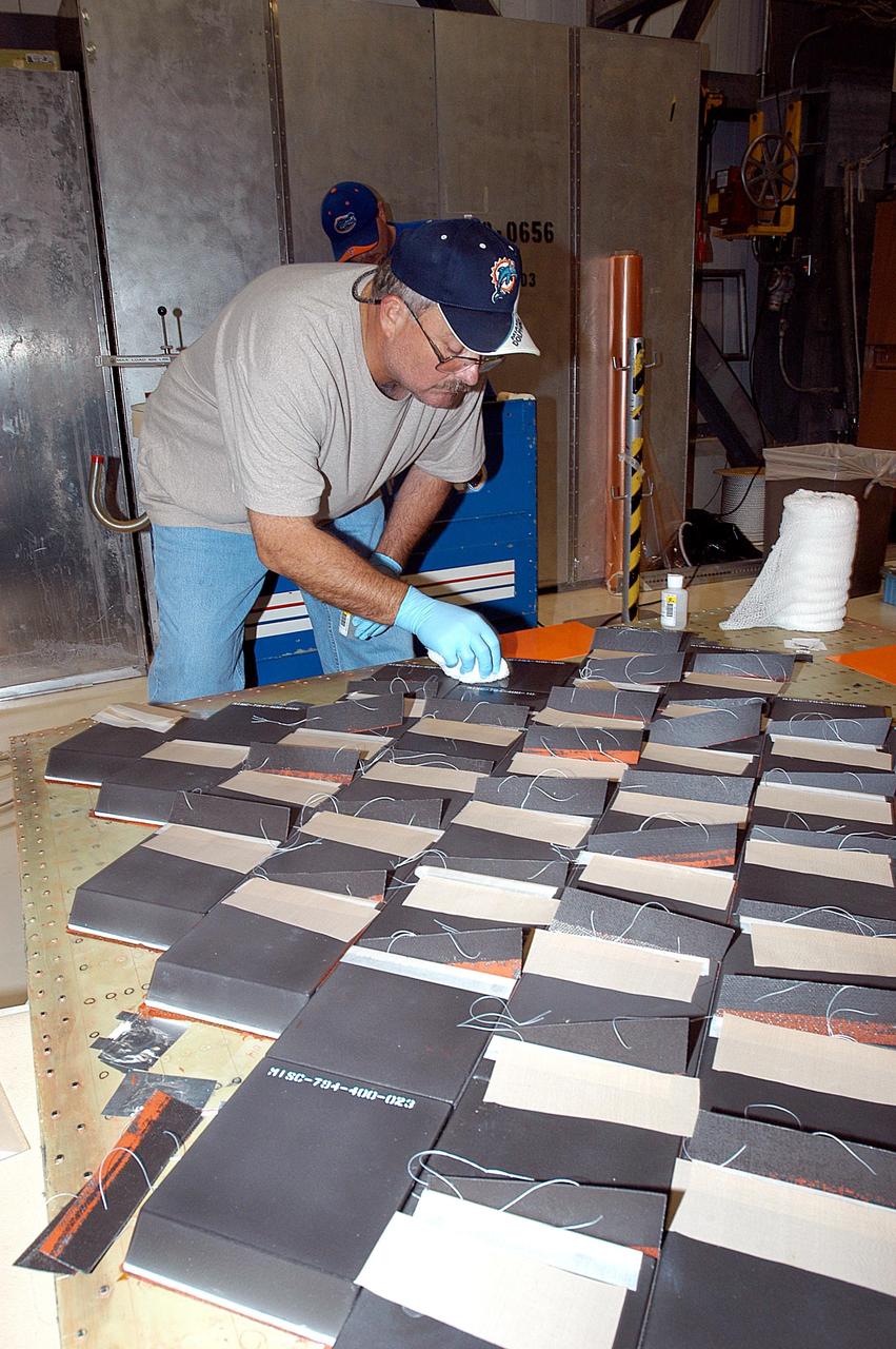 KENNEDY SPACE CENTER, FLA. -- In the Orbiter Processing Facility, United Space Alliance employee Dave Sanborn installs Thermal Protection System tiles on a main landing gear door of Space Shuttle orbiter Enterprise (OV-101). Sections of Enterprise were borrowed from the Smithsonian Institution's Air and Space Museum where the orbiter is being stored at the Washington Dulles International Airport. Enterprise was the first orbiter built in the Shuttle fleet and was used to conduct the Approach and Landing Test Program before the first powered Shuttle flight. After the tile installation is complete, the sections will be transferred to the Southwest Research Institute for testing requested by the Columbia Accident Investigation Board.