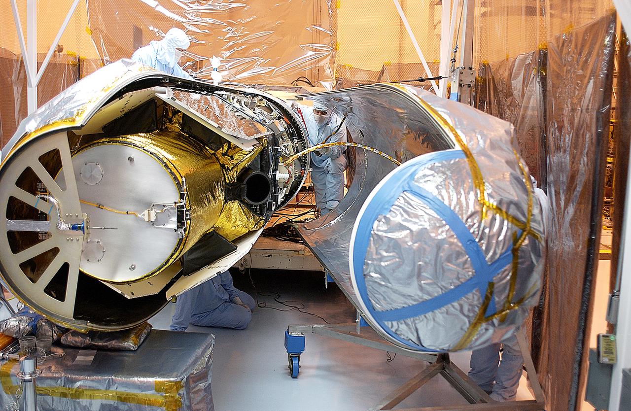 Workers in the Multi-Payload Processing Facility prepare to close the port fairing around the Galaxy Evolution Explorer (GALEX). The spacecraft is already mated to the Pegasus launch vehicle. After encapsulation, the GALEX/Pegasus will be transported to Cape Canaveral Air Force Station and mated to the L-1011 about four days before launch. A new launch date has not been determined.