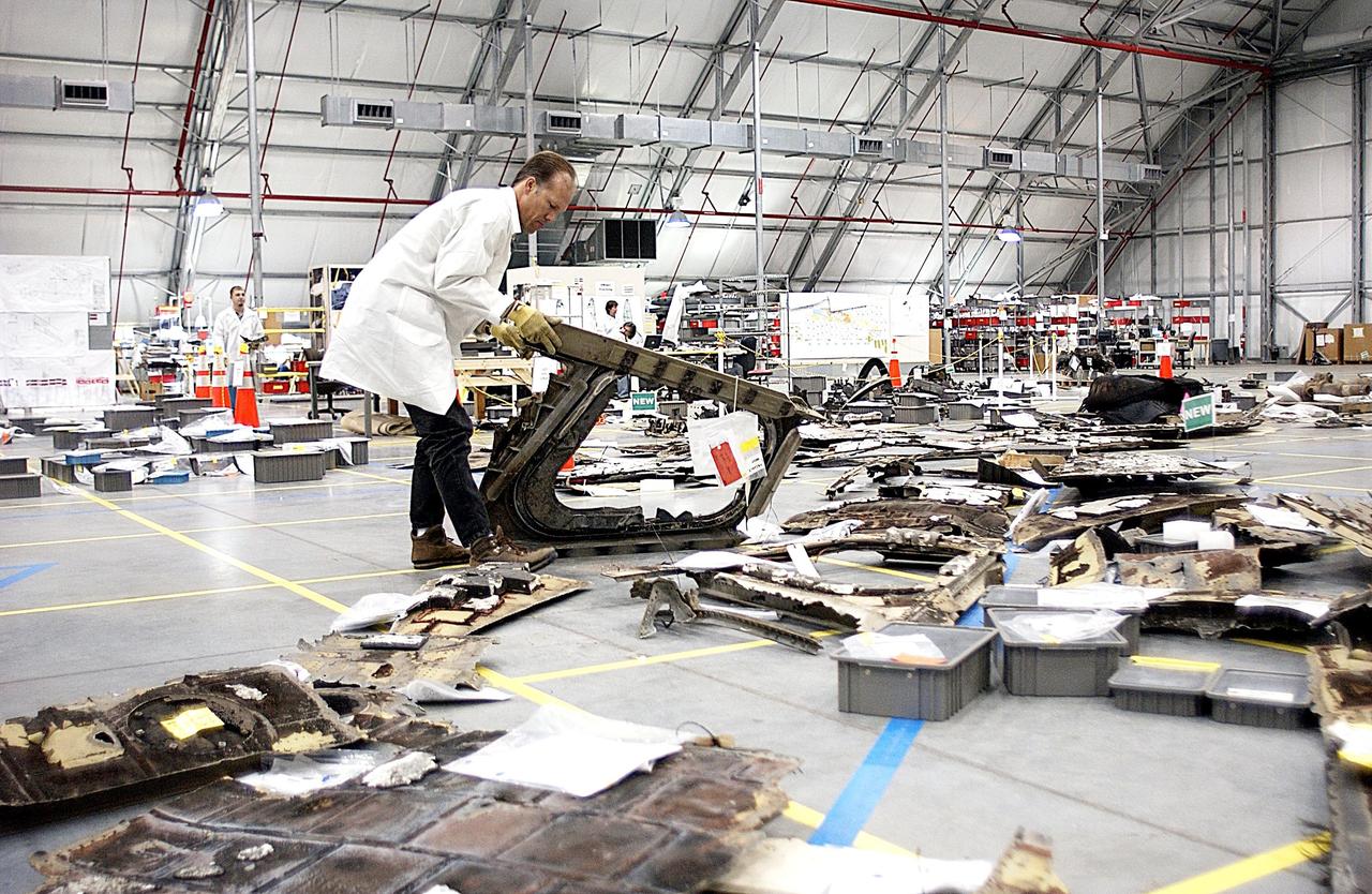 KENNEDY SPACE CENTER, FLA. -- A member of the Columbia Reconstruction Project Team examines a piece of Columbia debris on the floor of the KSC RLV Hangar. Shipped from Barksdale Air Force Base, Shreveport, La., more than 70,000 items, weighing 78,000 pounds, about 36 percent of the Shuttle by weight, have been delivered to KSC for use in the mishap investigation. Ground teams have completed 78 percent of their primary search area, and airborne crews finished 80 percent of their assigned area. Search teams have completed 98 percent of the underwater searches in Lake Nacogdoches and Toledo Bend Reservoir.