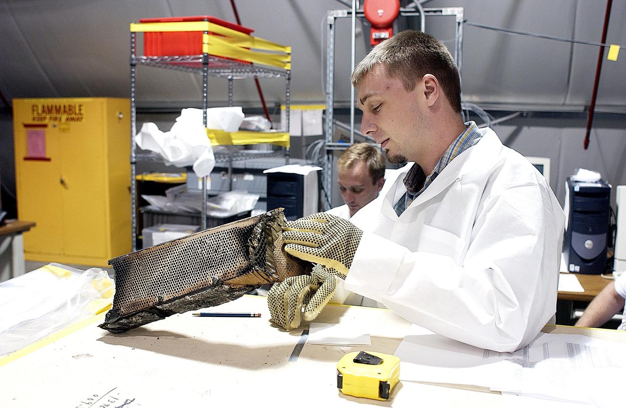 KENNEDY SPACE CENTER, FLA. -- A member of the Columbia Reconstruction Project Team examines a piece of Columbia debris for cataloging in the KSC RLV Hangar. Shipped from Barksdale Air Force Base, Shreveport, La., more than 70,000 items, weighing 78,000 pounds, about 36 percent of the Shuttle by weight, have been delivered to KSC for use in the mishap investigation. Ground teams have completed 78 percent of their primary search area, and airborne crews finished 80 percent of their assigned area. Search teams have completed 98 percent of the underwater searches in Lake Nacogdoches and Toledo Bend Reservoir.