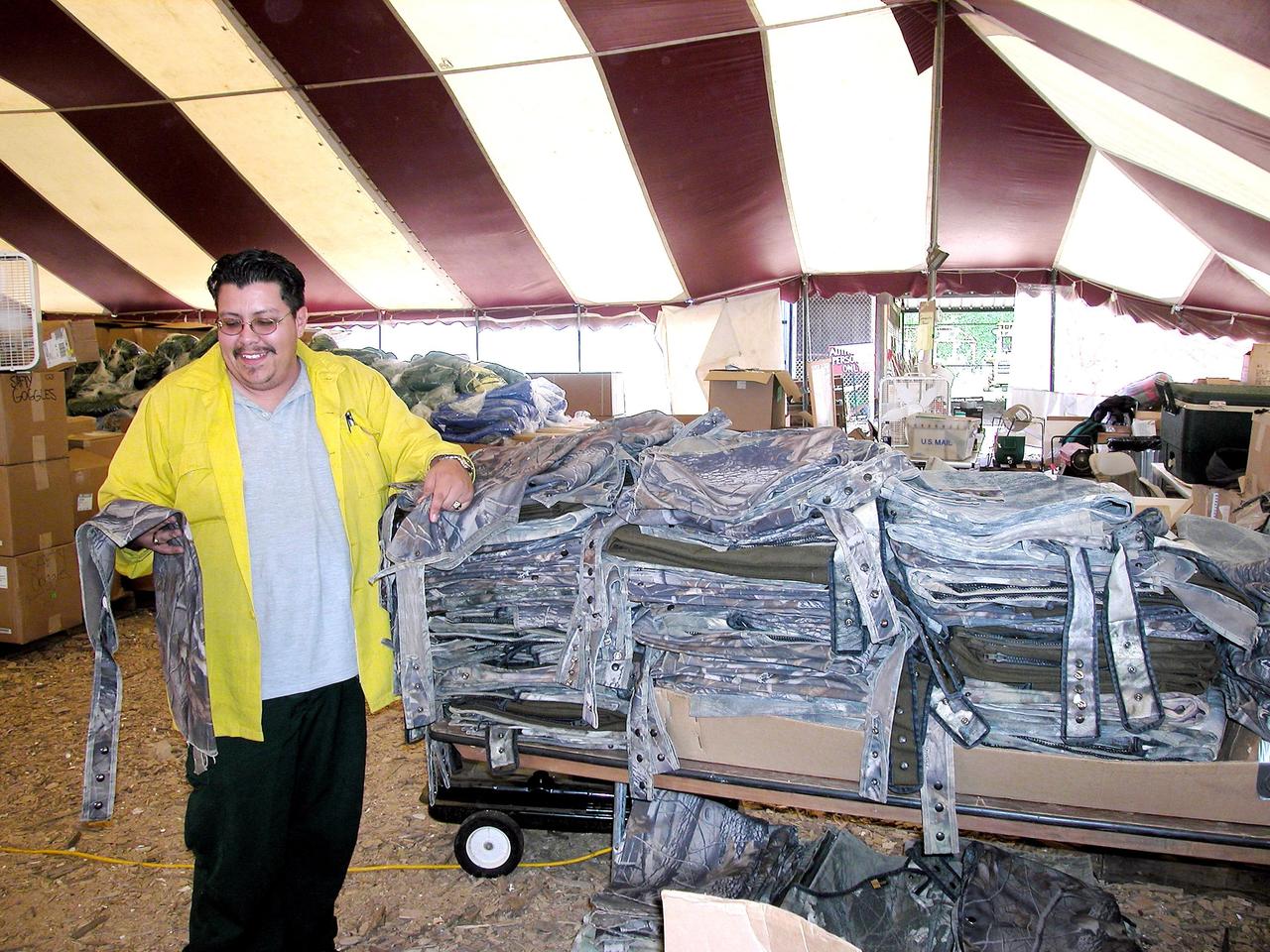 KENNEDY SPACE CENTER, FLA. -- Temporary camp worker Michael Trujillo of North New Mexico displays chaps in the supply tent at the Nacogdoches site. The chaps are used by U.S. Forest Service, Environmental Protection Agency and space program workers searching through dense forests in East Texas. Kennedy Space Center workers are participating in the Columbia Recovery efforts at the Lufkin (Texas) Command Center, four field sites in East Texas, and the Barksdale, La., hangar site. KSC is working with representatives from other NASA Centers and with those from a number of federal, state and local agencies in the recovery effort. KSC provides vehicle technical expertise in the field to identify, collect and return Shuttle hardware to KSC.