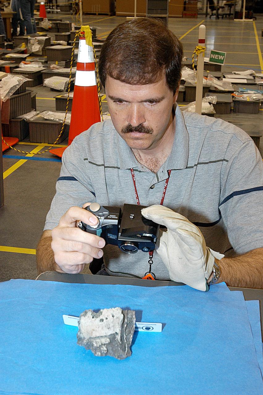 KENNEDY SPACE CENTER, FLA. -- A member of the Columbia Reconstruction Project team photographs a piece of Columbia debris delivered to the RLV Hangar. Shipped from Barksdale Air Force Base, Shreveport, La., more than 70,000 items, weighing 78,000 pounds, about 36 percent of the Shuttle by weight, have been delivered to KSC for use in the mishap investigation. Ground teams have completed 78 percent of their primary search area, and airborne crews finished 80 percent of their assigned area. Search teams have completed 98 percent of the underwater searches in Lake Nacogdoches and Toledo Bend Reservoir.