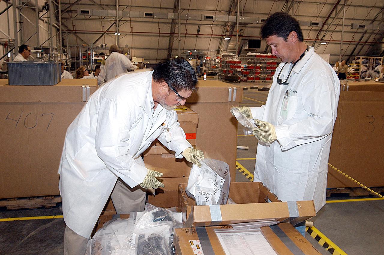 KENNEDY SPACE CENTER, FLA. -- Members of the Columbia Reconstruction Project team unpack pieces of Columbia debris delivered to the RLV Hangar. Shipped from Barksdale Air Force Base, Shreveport, La., more than 70,000 items, weighing 78,000 pounds, about 36 percent of the Shuttle by weight, have been delivered to KSC for use in the mishap investigation. Ground teams have completed 78 percent of their primary search area, and airborne crews finished 80 percent of their assigned area. Search teams have completed 98 percent of the underwater searches in Lake Nacogdoches and Toledo Bend Reservoir.