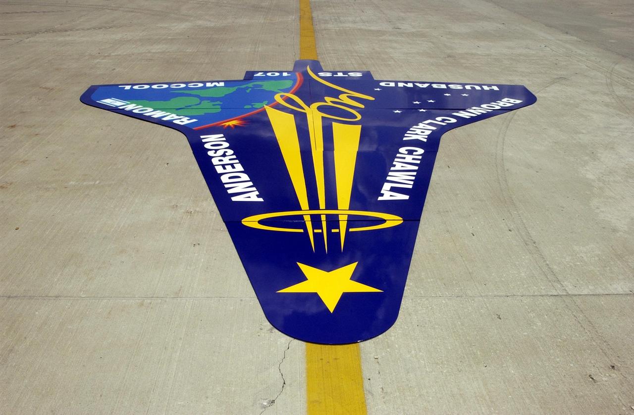 KENNEDY SPACE CENTER, FLA. -- An enlarged replica of the STS-107 crew emblem is delivered to the RLV Hangar where it will be installed on an outside wall.  Inside the hangar, members of the Columbia Reconstruction Project team are identifying pieces of Columbia debris as they arrive at Kennedy Space Center and placing them on a grid approximating the shape of the orbiter.