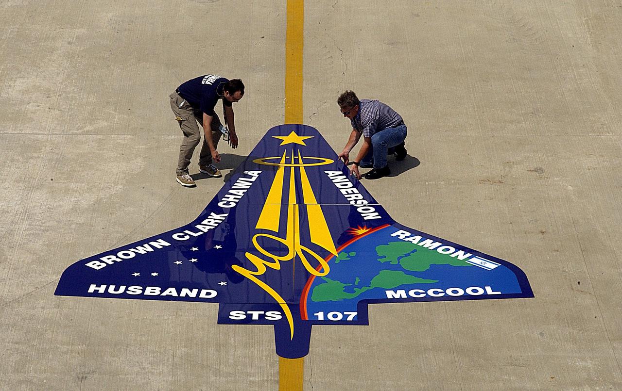 KENNEDY SPACE CENTER, FLA. -- Workers deliver an enlarged replica of the STS-107 crew emblem to the RLV Hangar where it will be installed on an outside wall. Inside the hangar, members of the Columbia Reconstruction Project team are identifying pieces of Columbia debris as they arrive at Kennedy Space Center and placing them on a grid approximating the shape of the orbiter.