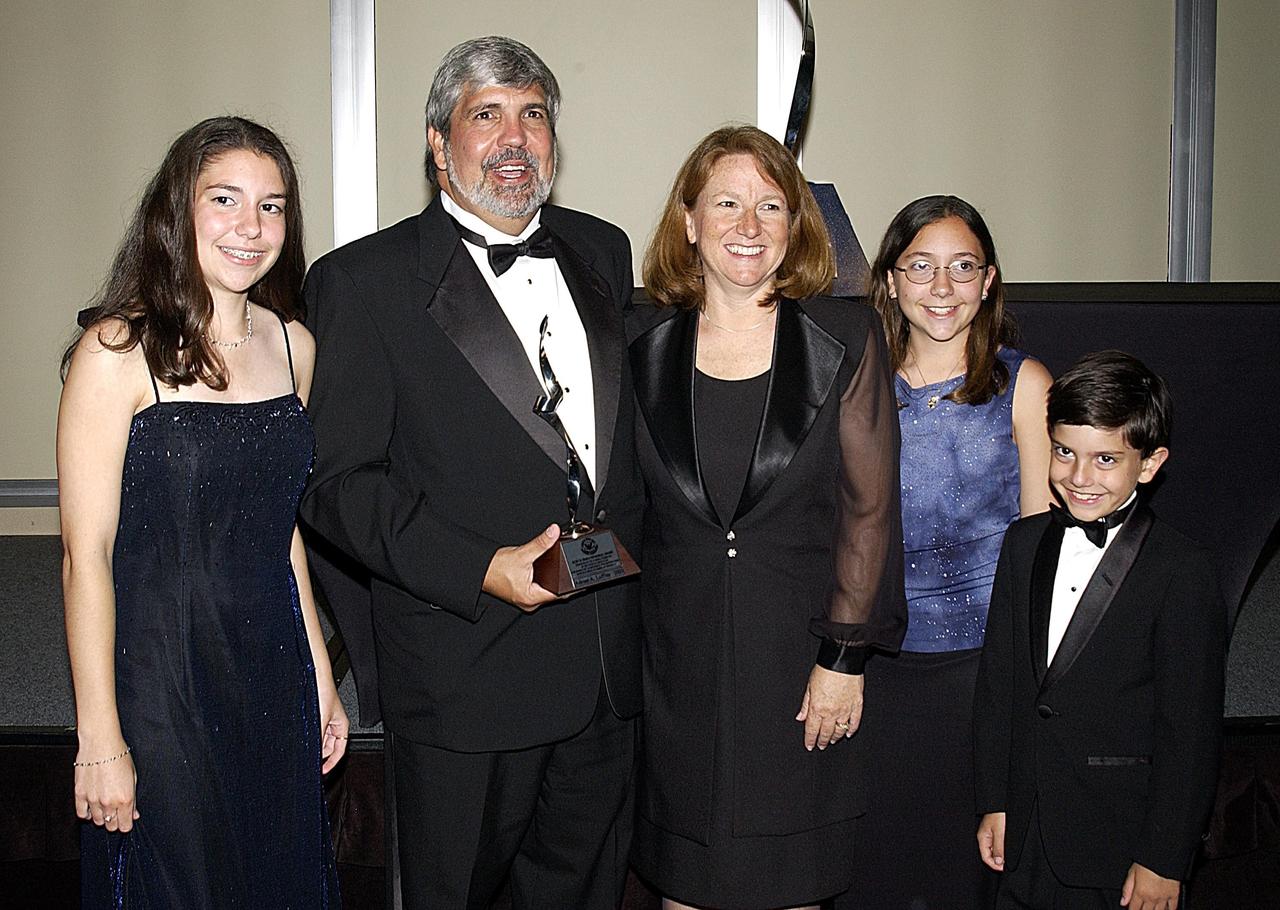 KENNEDY SPACE CENTER, FLA. -- Adrian Laffitte (second from left) and his family enjoy a moment in the spotlight at a formal dinner held in the Debus Conference Center at the Kennedy Space Center Visitor Complex. Laffitte, director of Atlas Programs for Lockheed Martin Astronautics at Cape Canaveral Air Force Station, was honored as the winner of the 2003 Dr. Kurt H. Debus Award from the National Space Club Florida Committee. The Debus Award was created by the committee to recognize significant achievements and contributions made in Florida to American aerospace efforts.