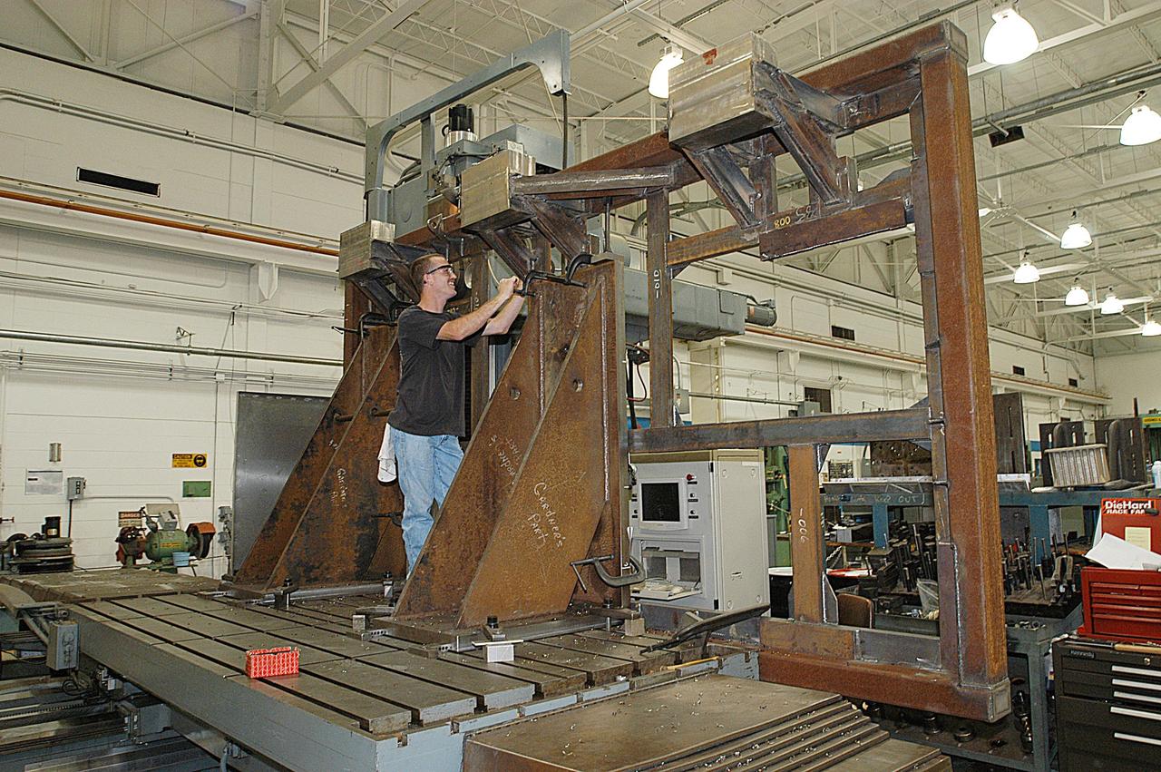 KENNEDY SPACE CENTER, FLA. -- United Space Alliance technician Matt Boonstra works on a main landing gear door mounting fixture in the Launch Equipment Shop. The fixture is being used to support the Columbia mishap investigation.  A simulated orbiter wing and several test panels, along with sections of Space Shuttle orbiter Enterprise (OV-101), will be transferred to the Southwest Research Institute for testing after Thermal Protection System (TPS) tile installation on them is complete. The testing has been requested by the Columbia Accident Investigation Board. For this initiative, sections of Enterprise were borrowed from the Smithsonian Institution's Air and Space Museum where the orbiter is being stored at the Washington Dulles International Airport. Enterprise was the first orbiter built in the Shuttle fleet and was used to conduct the Approach and Landing Test Program before the first powered Shuttle flight.