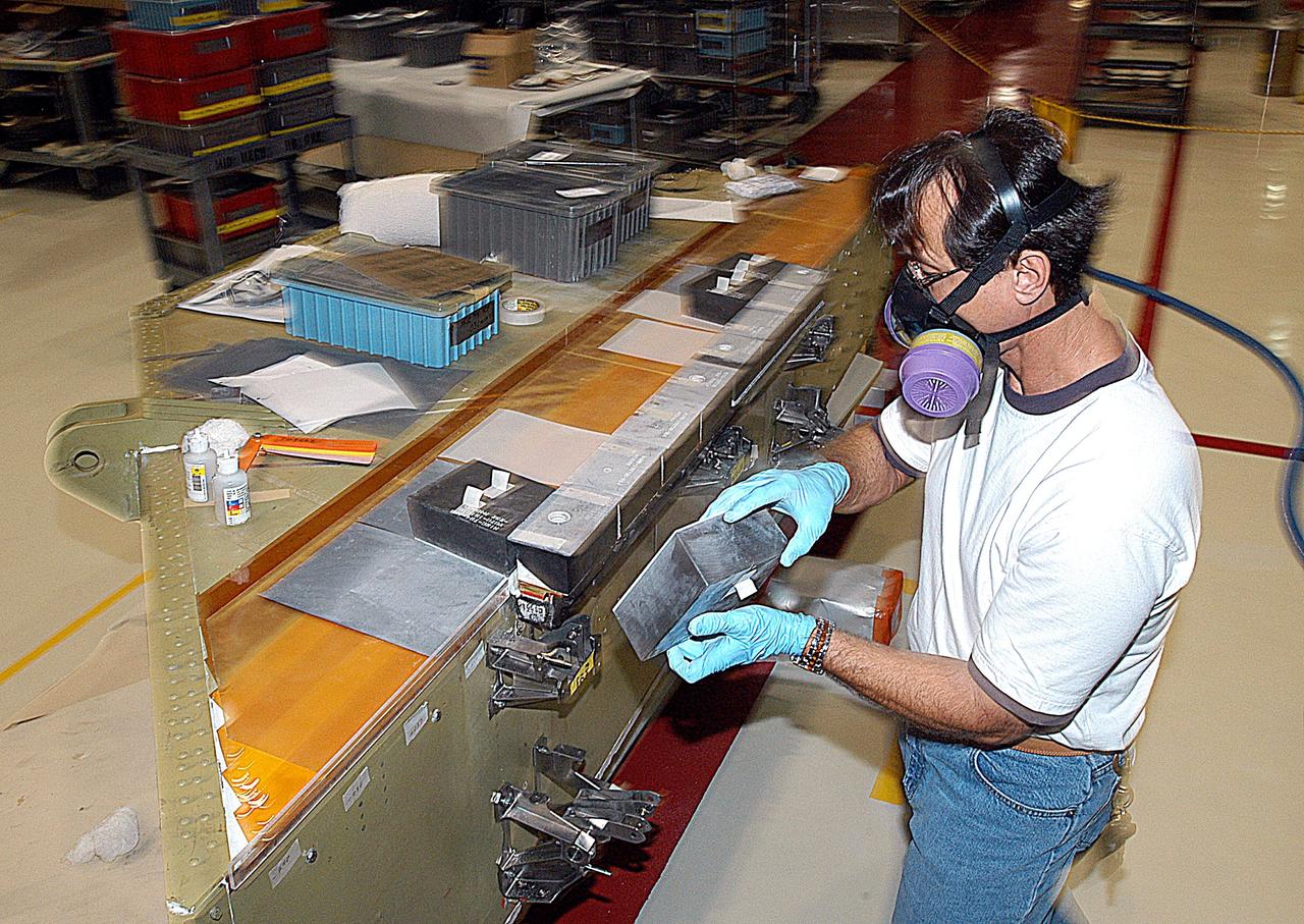 KENNEDY SPACE CENTER, FLA. -- In the Orbiter Processing Facility (OPF), United Space Alliance (USA) technician Mark Jetton installs Thermal Protection System (TPS) tile on a simulated orbiter wing.  The wing, along with sections of Space Shuttle orbiter Enterprise (OV-101), will be transferred to the Southwest Research Institute for testing after the tile installation is complete. The testing has been requested by the Columbia Accident Investigation Board. For this initiative, sections of Enterprise were borrowed from the Smithsonian Institution's Air and Space Museum where the orbiter is being stored at the Washington Dulles International Airport. Enterprise was the first orbiter built in the Shuttle fleet and was used to conduct the Approach and Landing Test Program before the first powered Shuttle flight.